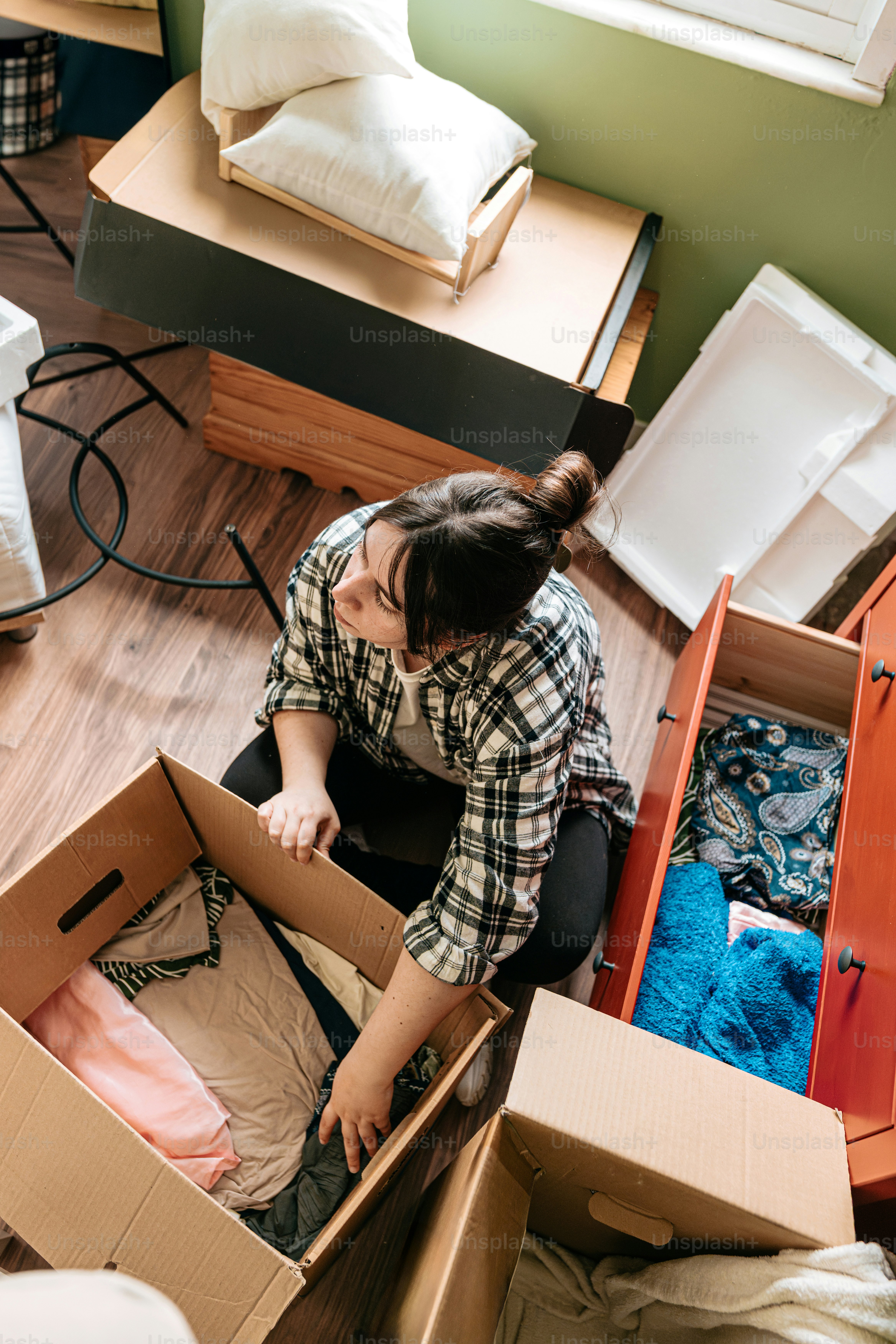 Woman packs clothes and belongings during a move.