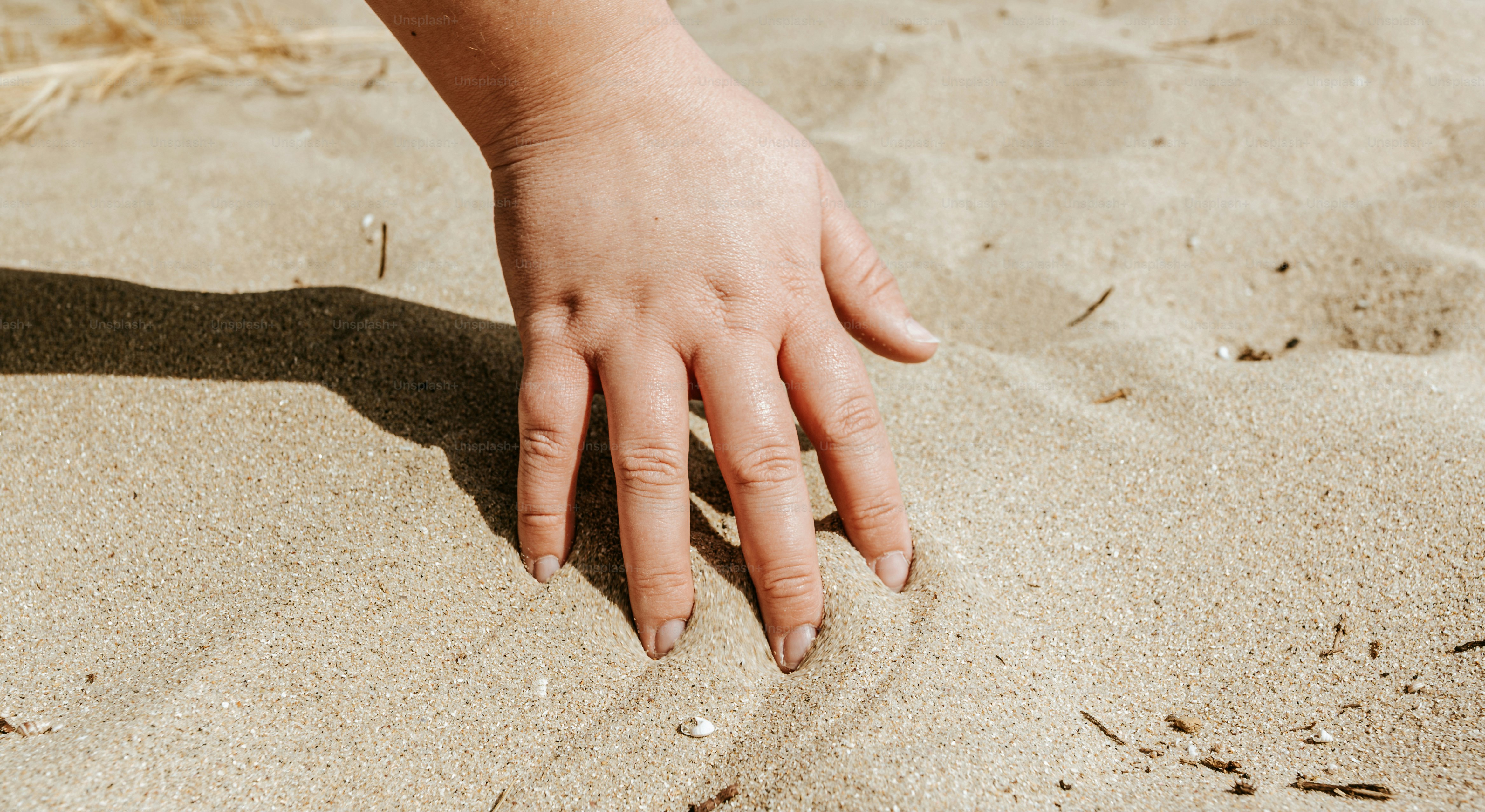A hand touches the sand