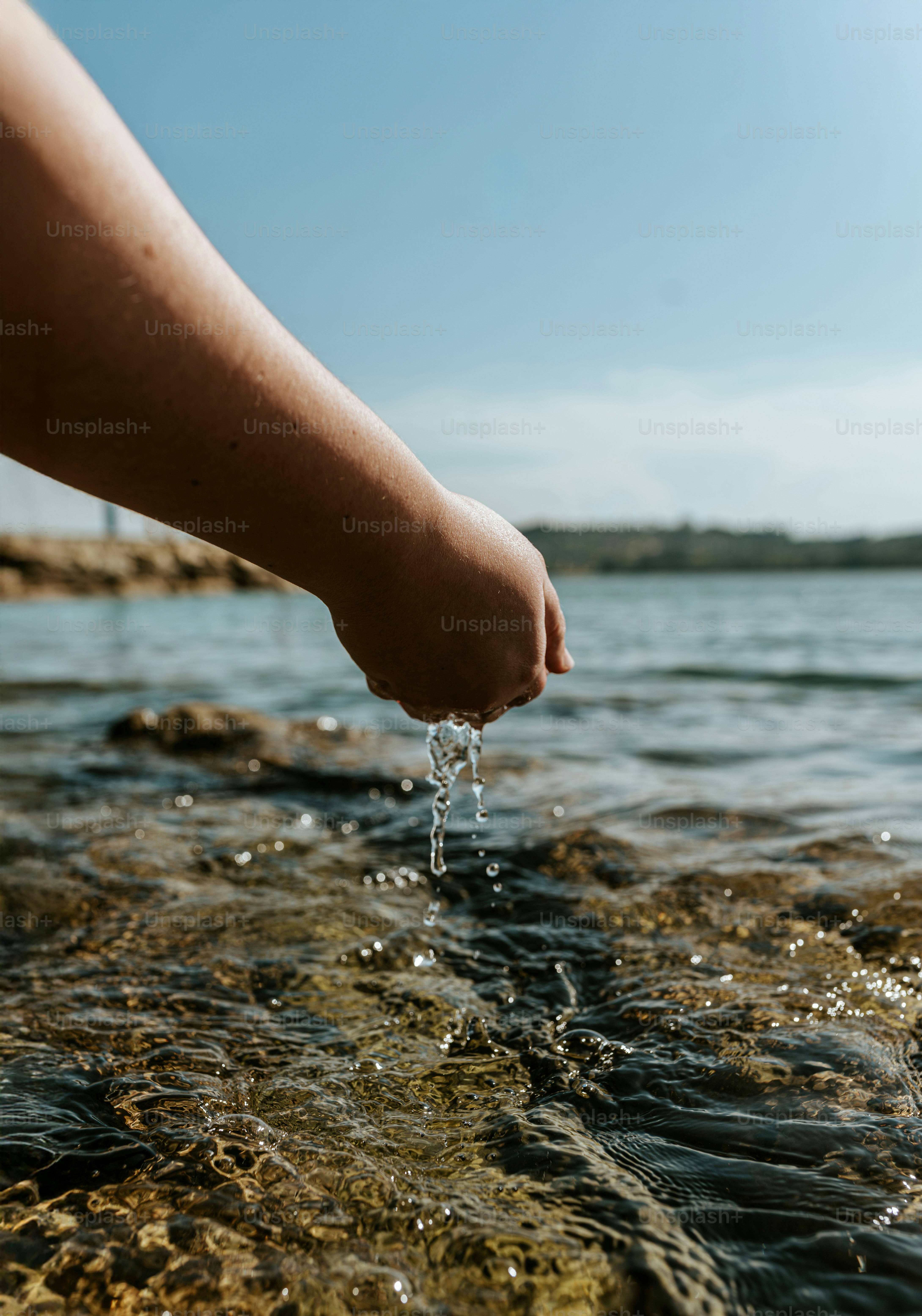 La mano gotea agua en el mar brillante
