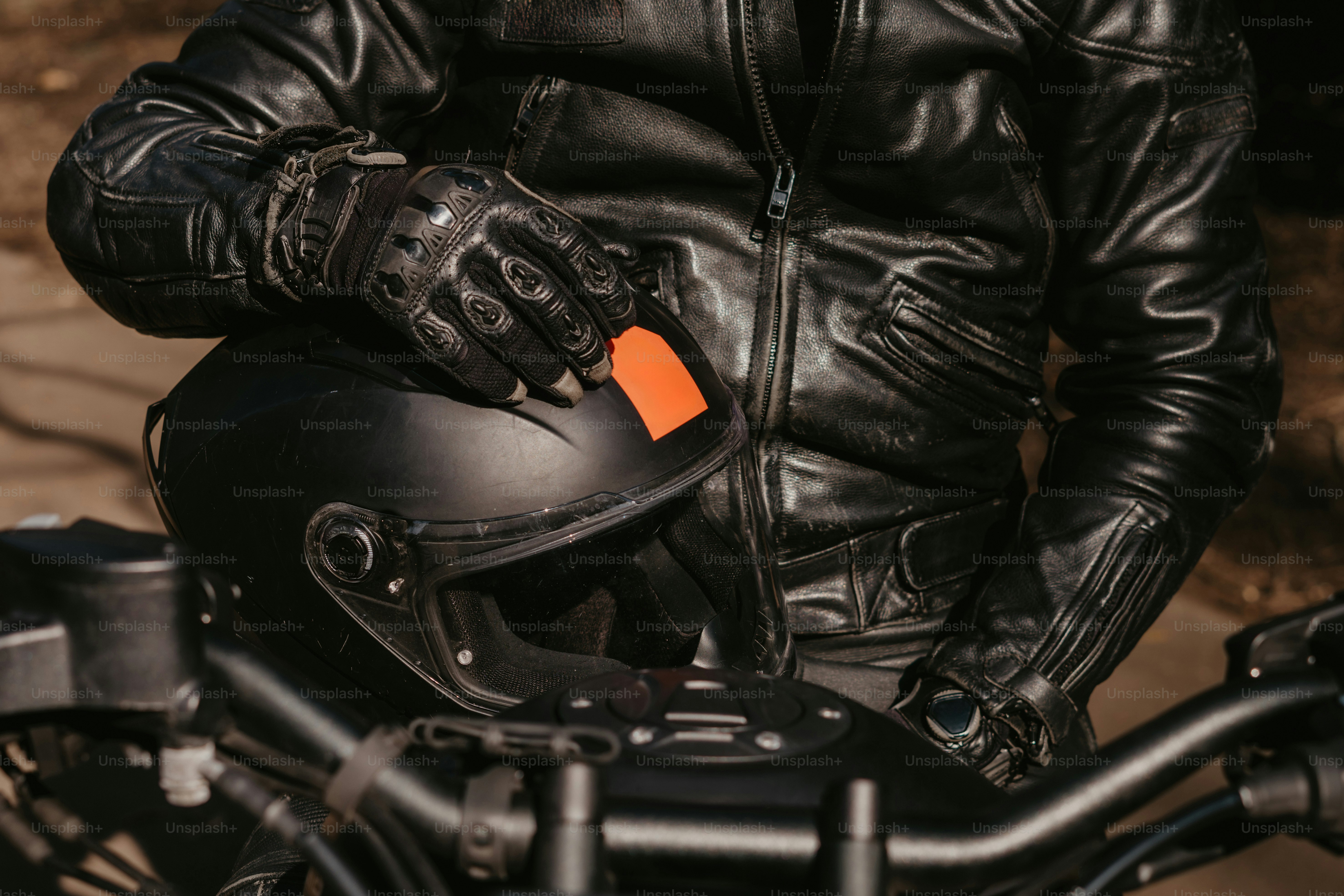 A motorcyclist with their helmet and leather jacket.