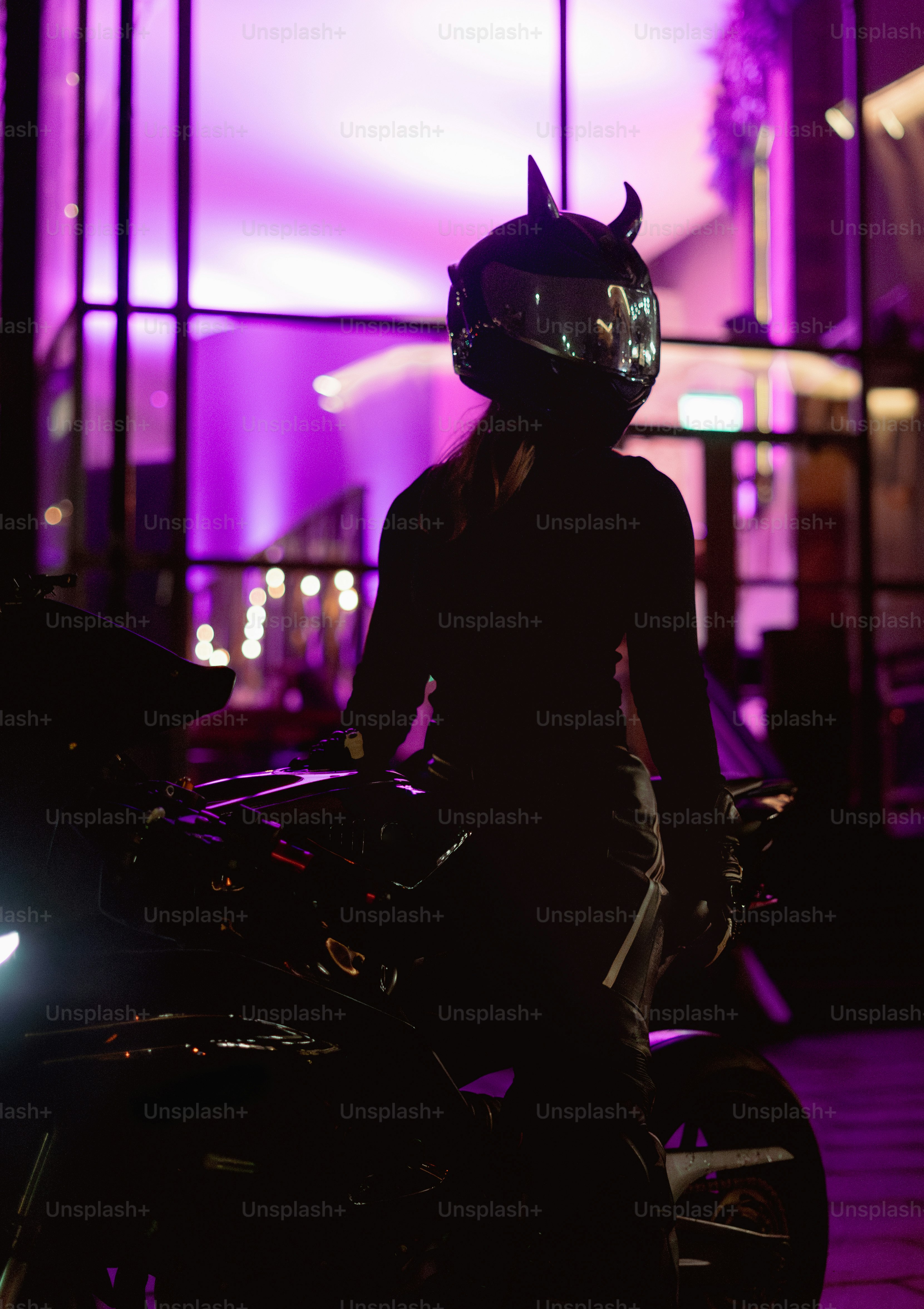 A person with a devil-horn helmet next to a motorcycle.