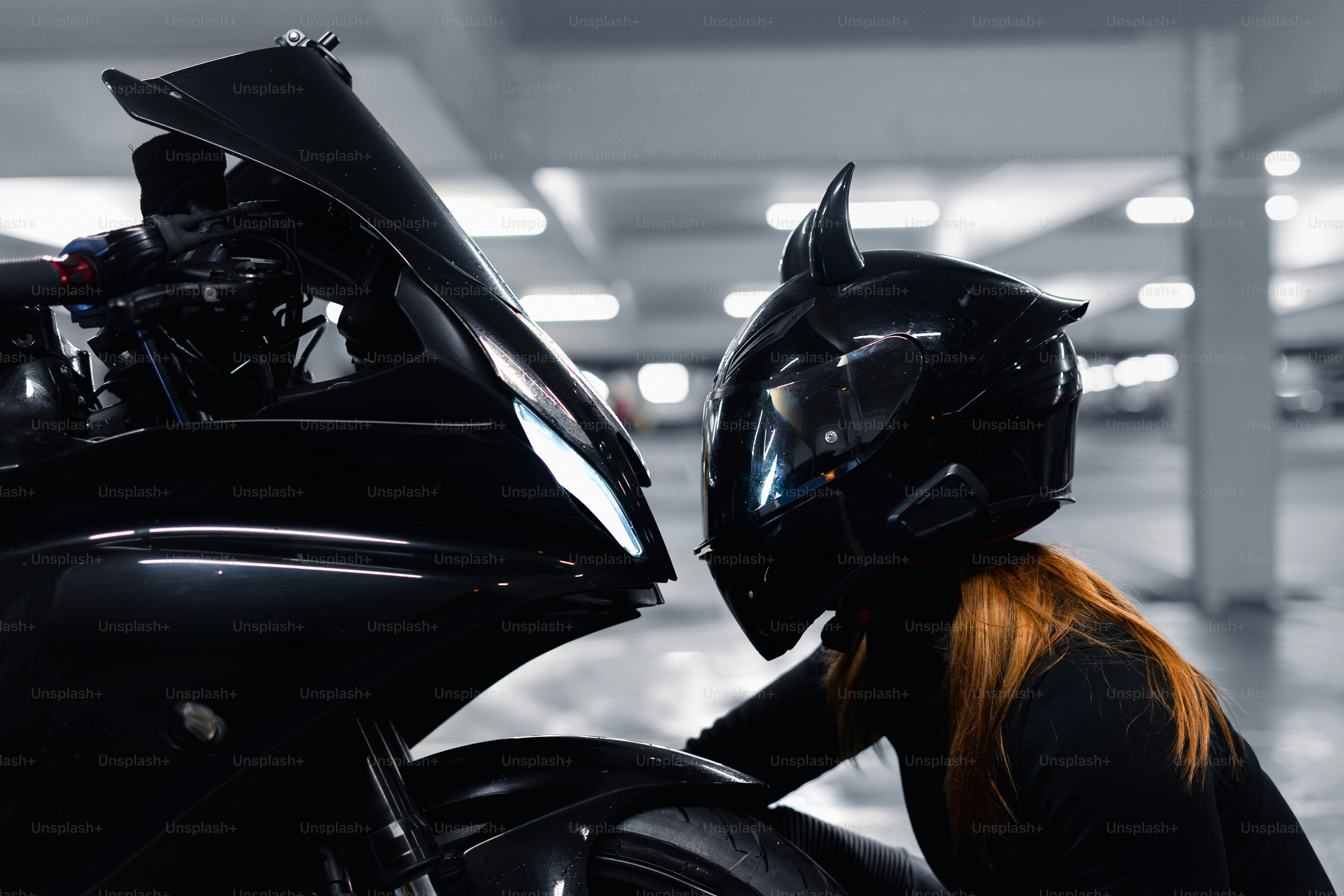 A woman admiring her black motorcycle.