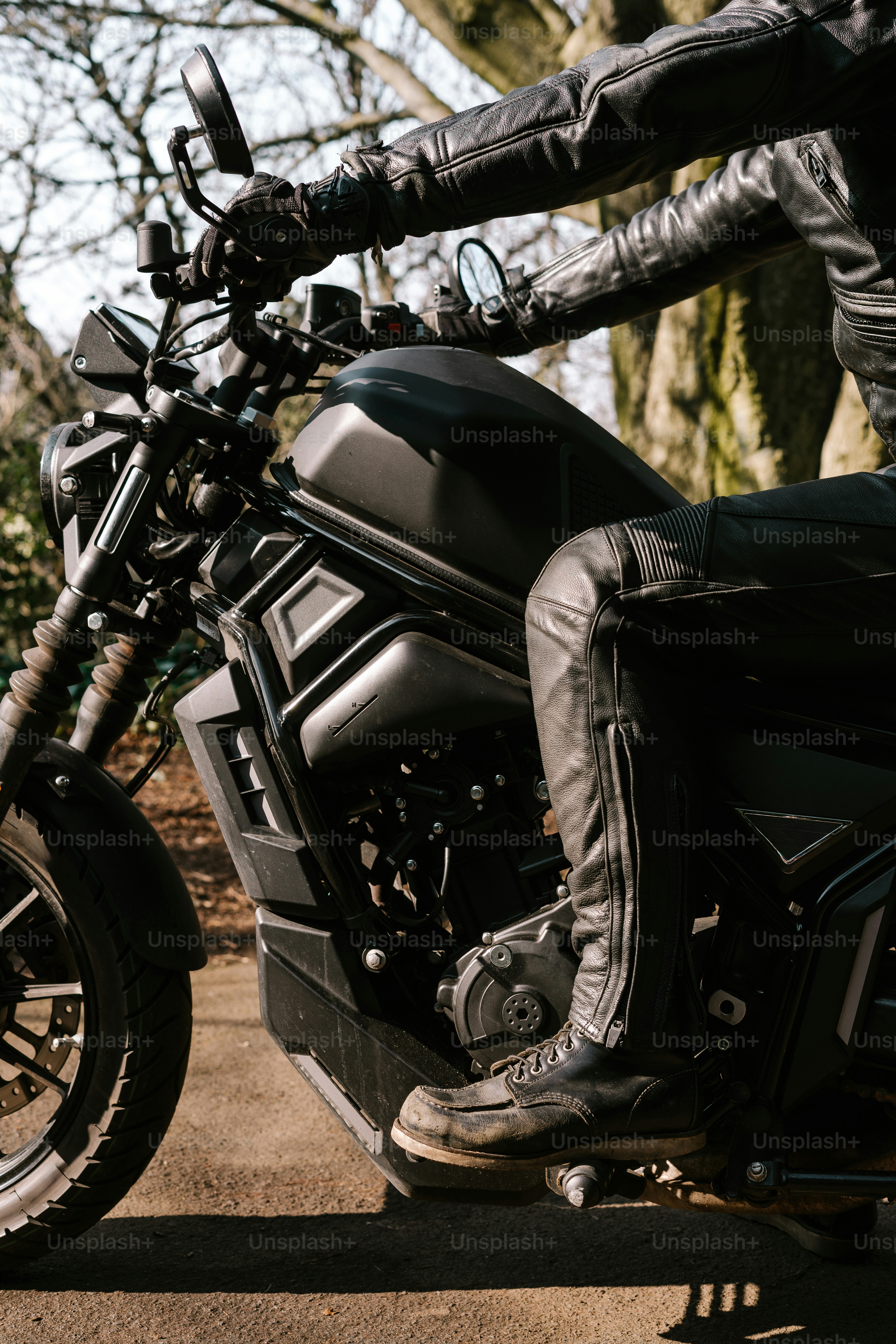 Motard en cuir noir à califourchon sur une moto.