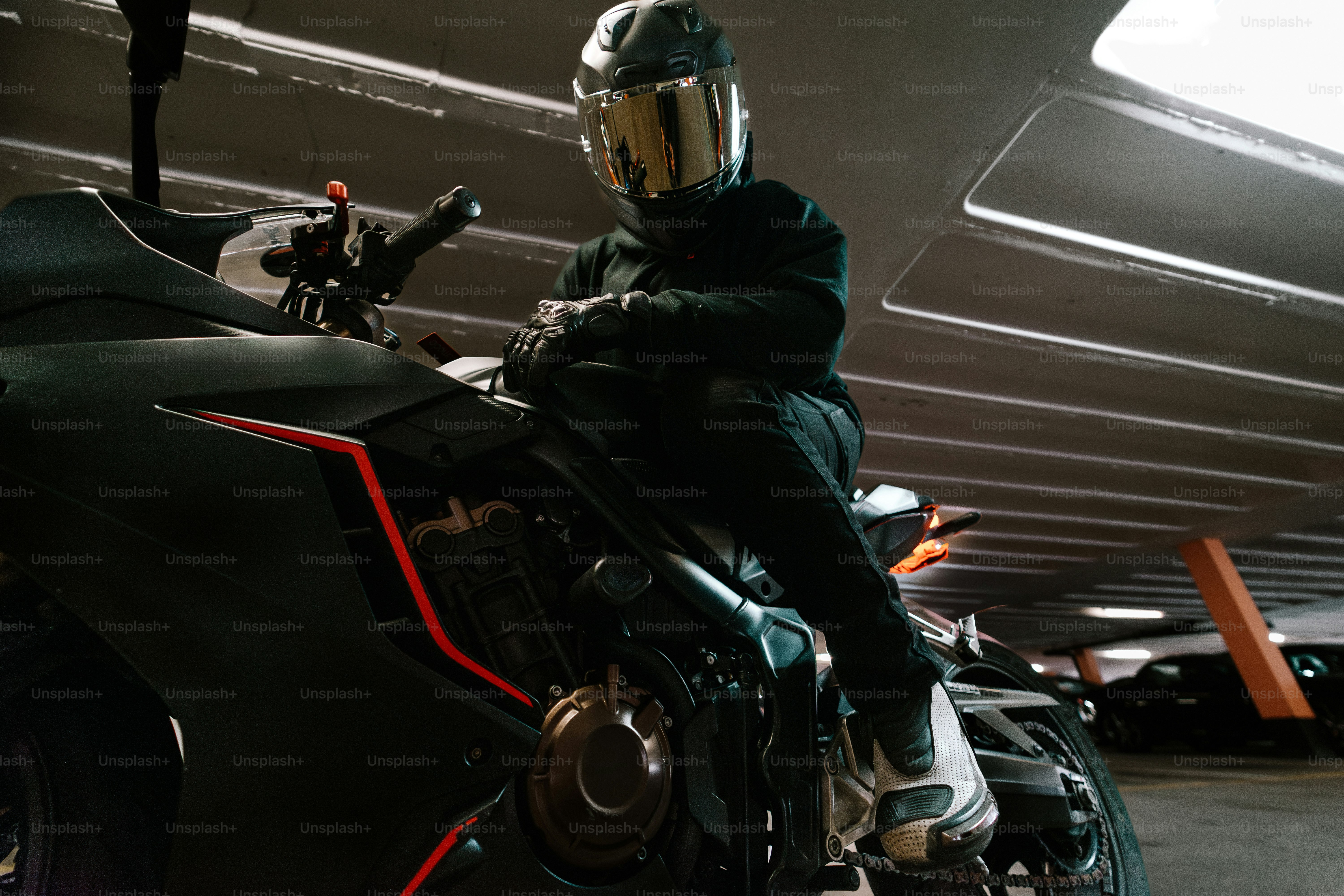 Motorcyclist sits on bike inside of a parking garage.