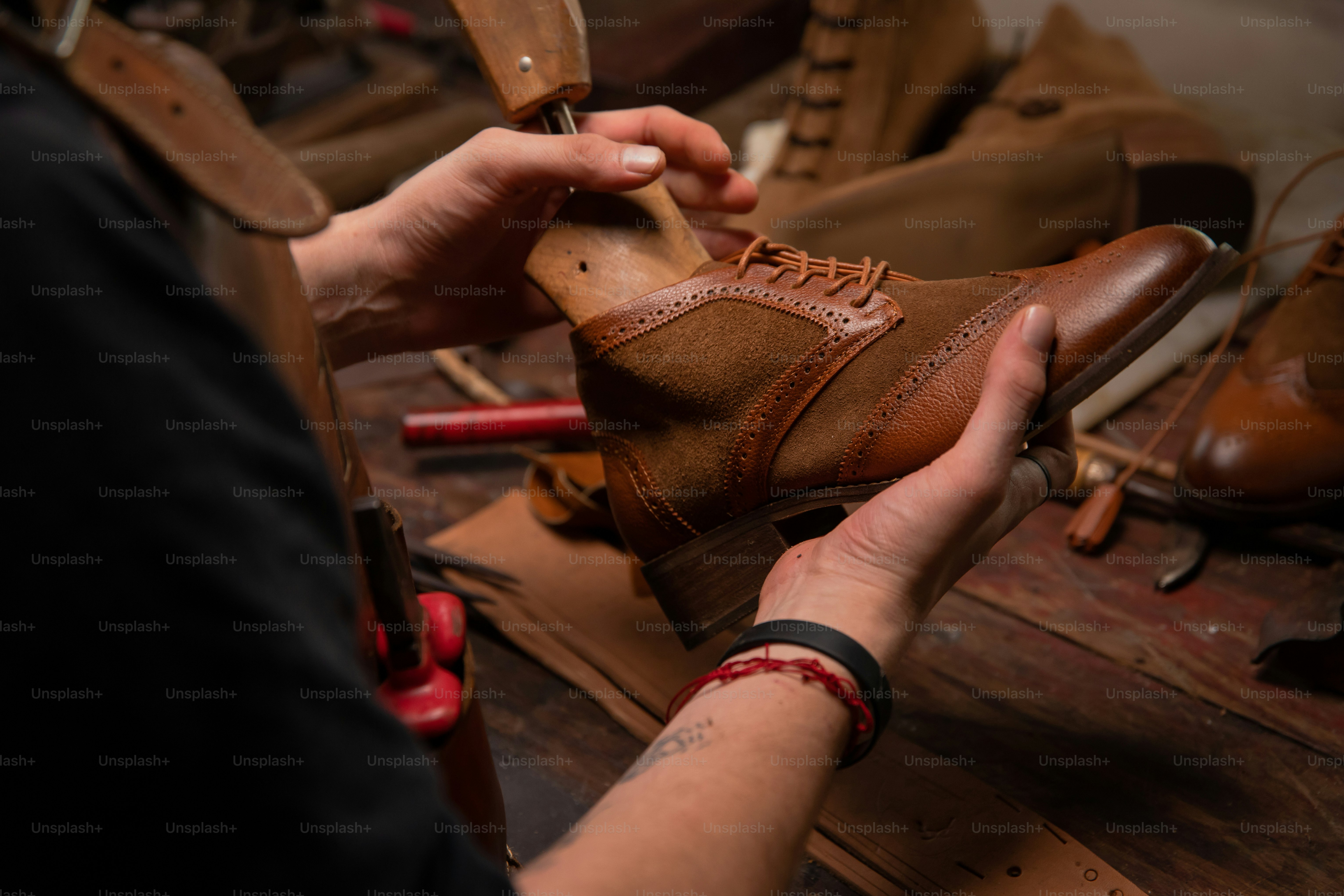 Seorang pembuat sepatu dengan hati-hati memeriksa sepatu kulit.