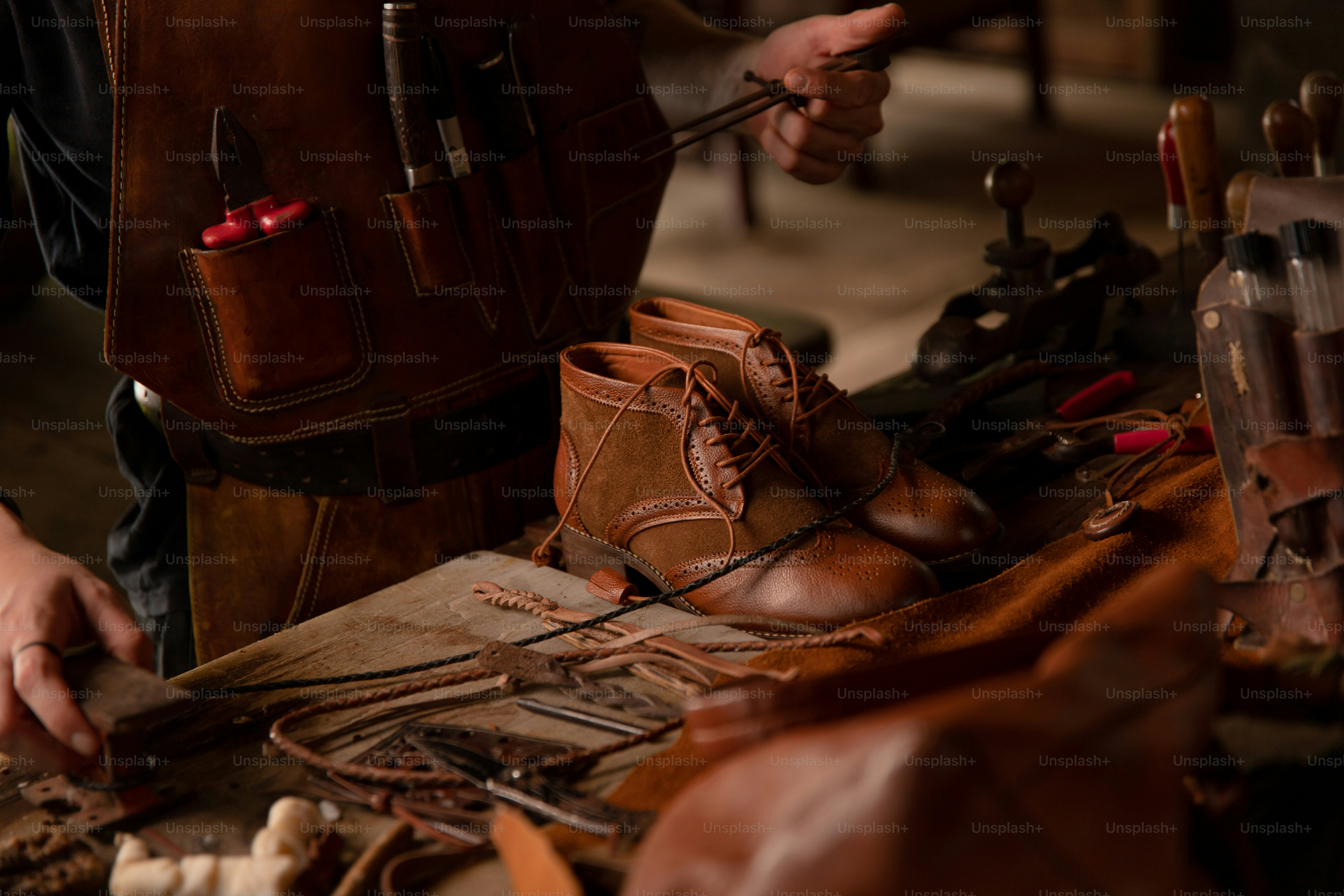 Um sapateiro está trabalhando em botas de couro marrom.