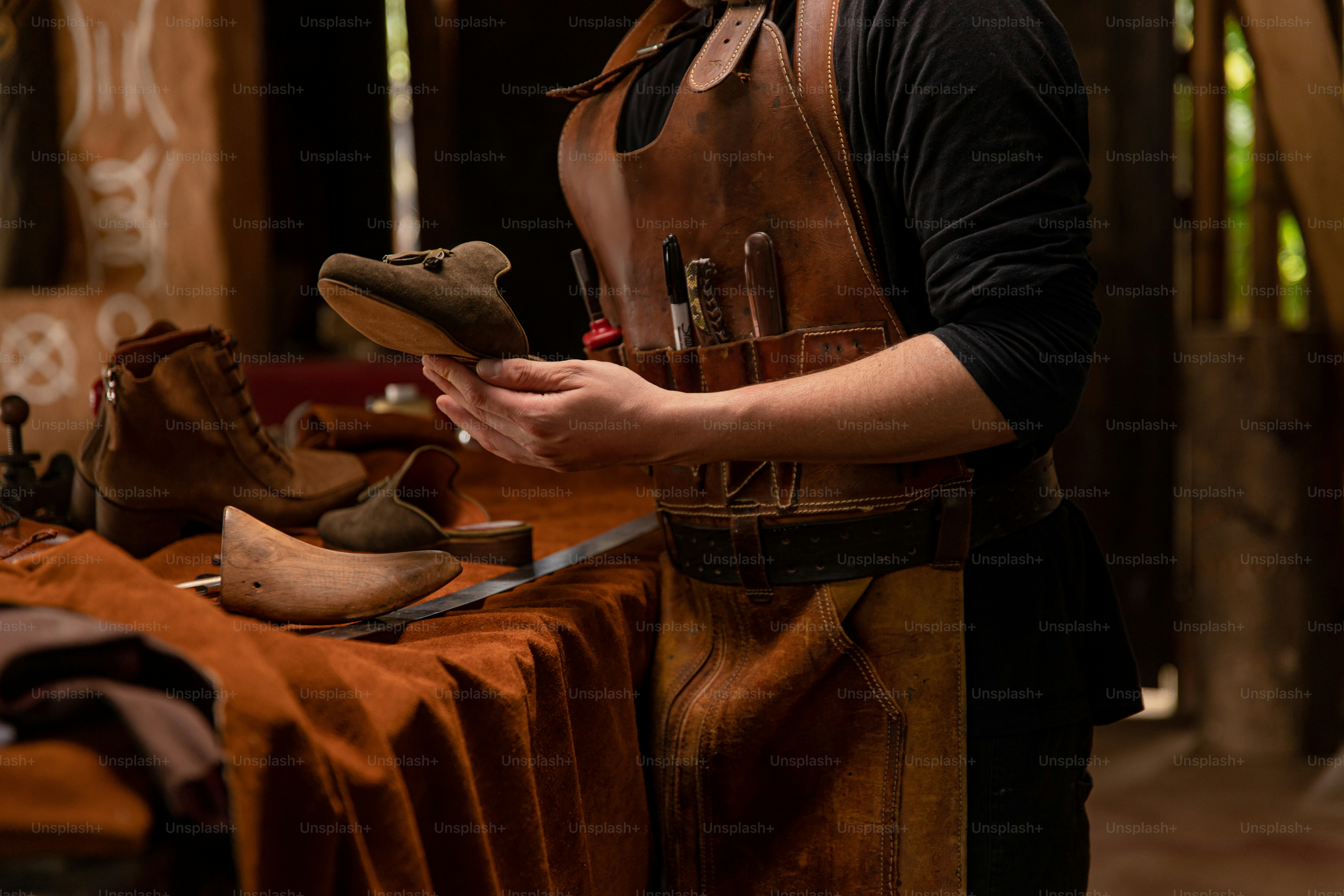 A cobbler examines a shoe in his workshop.