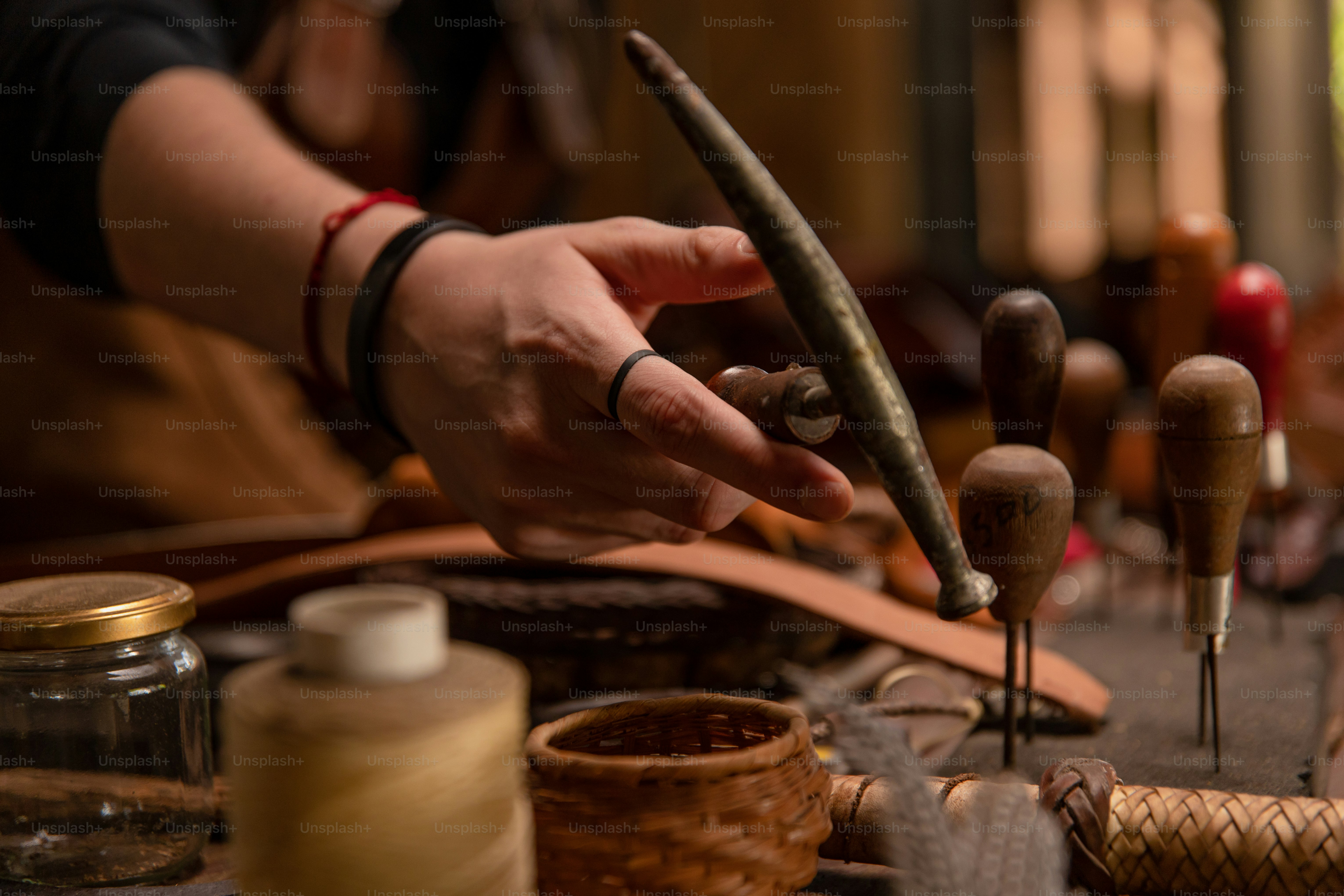 Leather craftsman uses tools in a workshop.