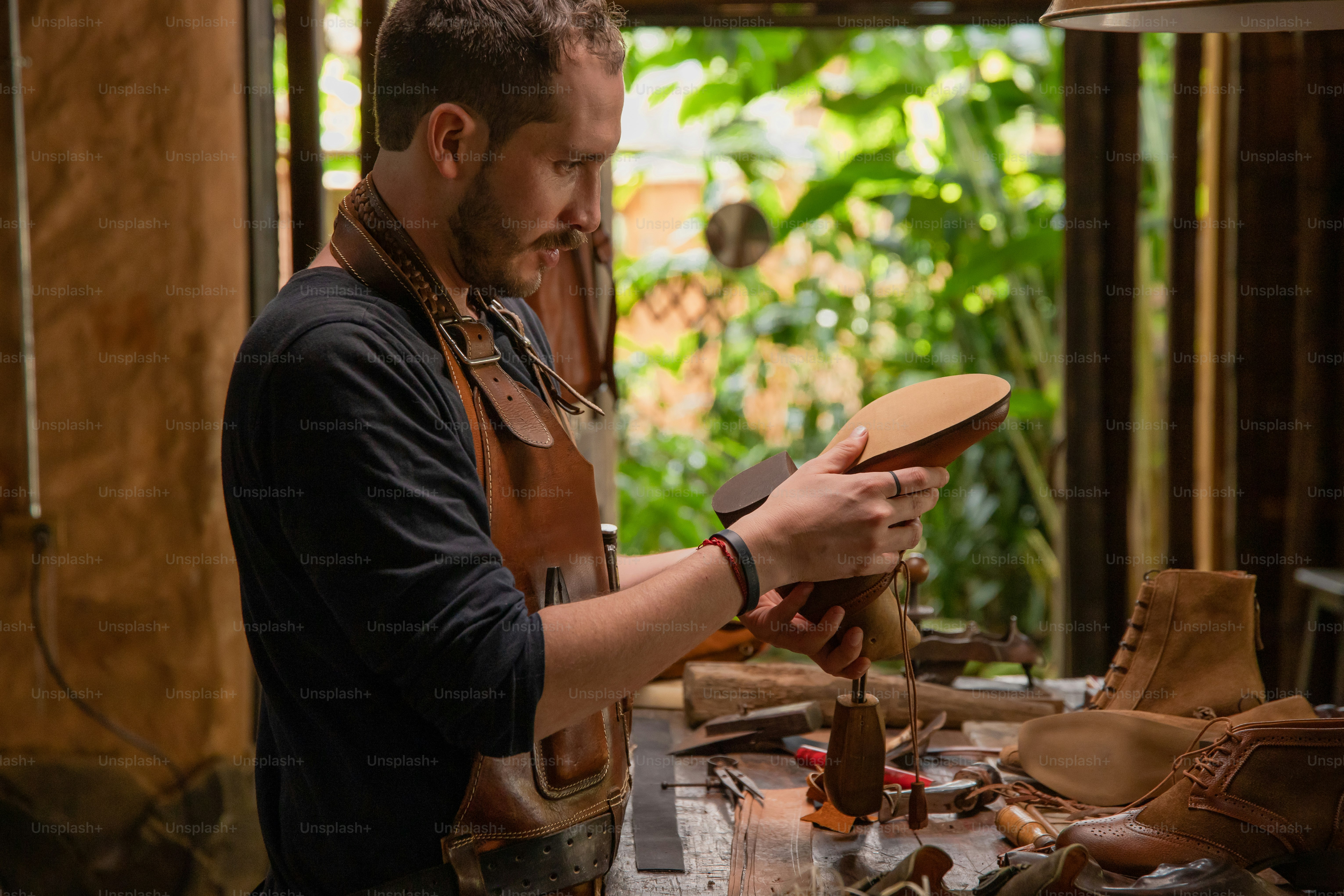 Shoemaker carefully works on a leather boot. photo – Luxury Image on ...