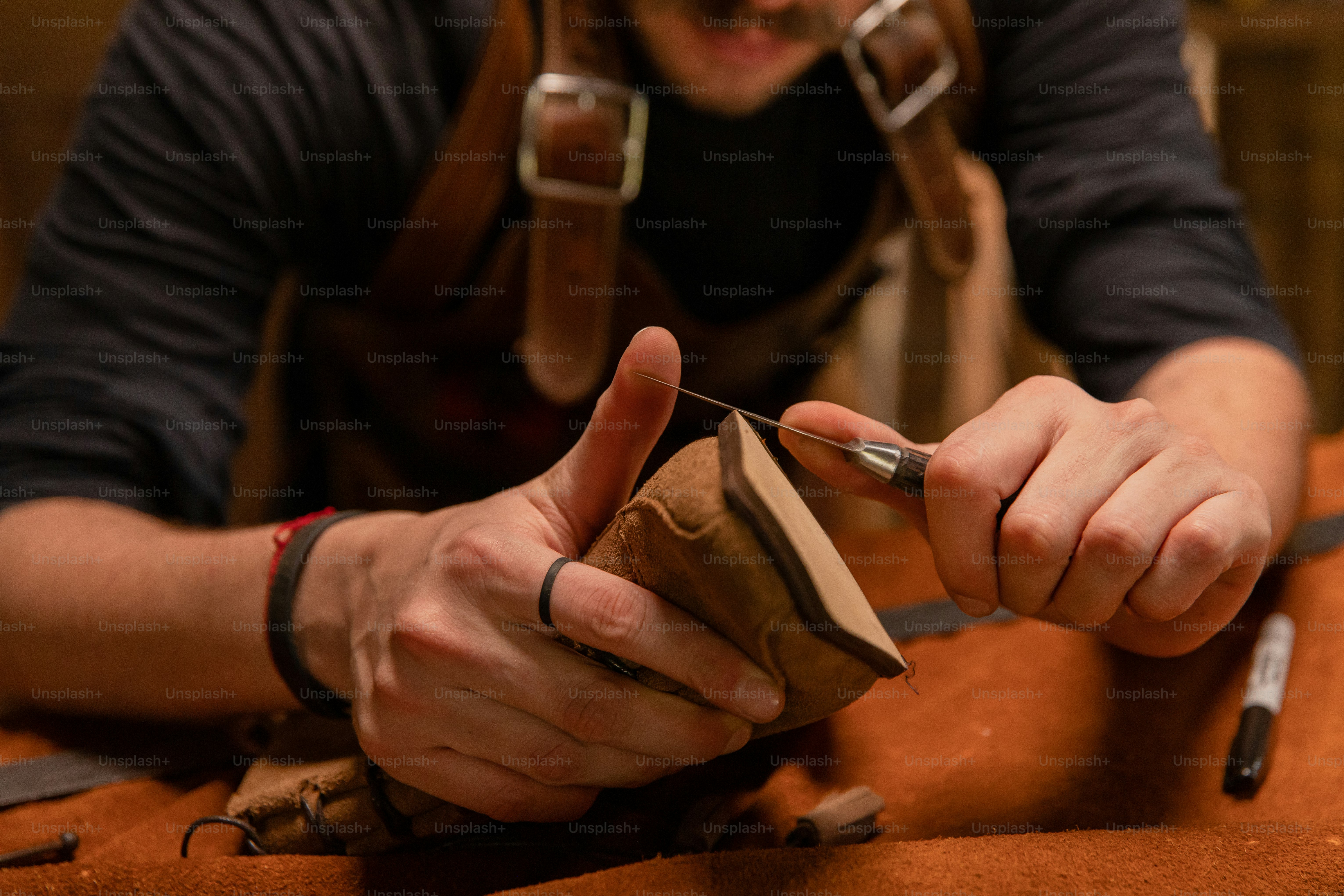 A craftsman is carefully working with leather.
