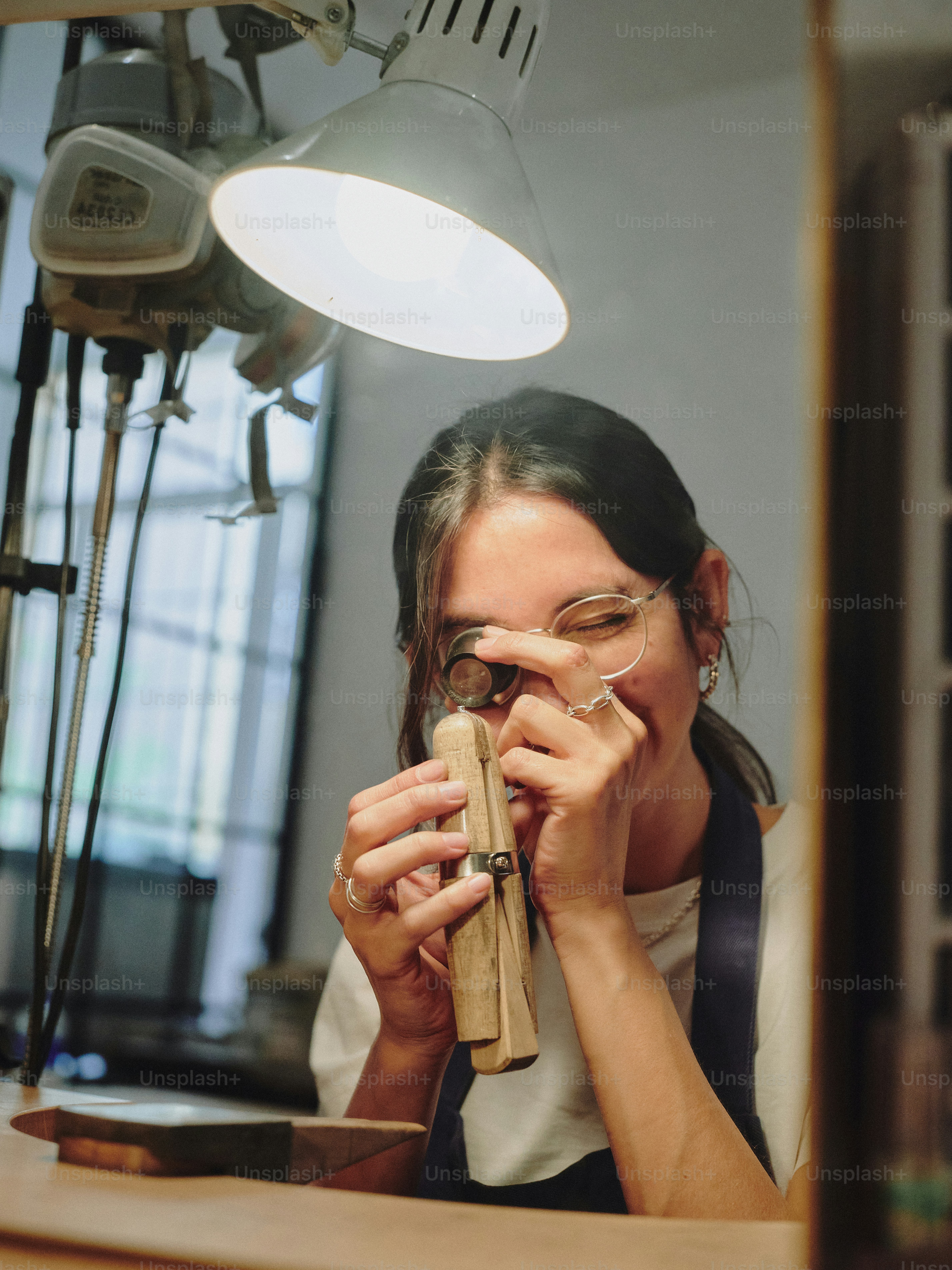 Woman intently examines jewelry with a magnifying glass.