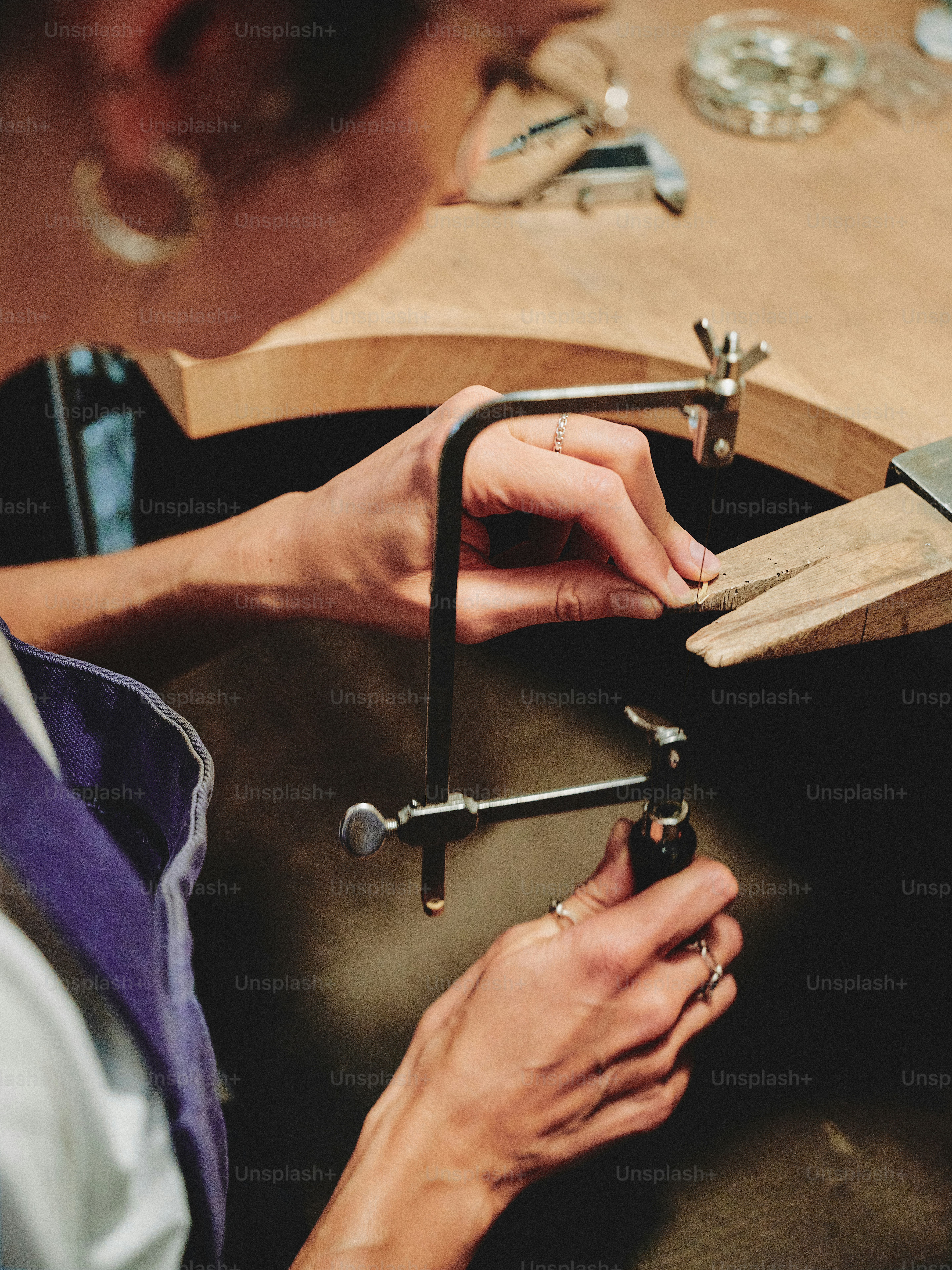 A jeweler is using a saw to work on a piece.
