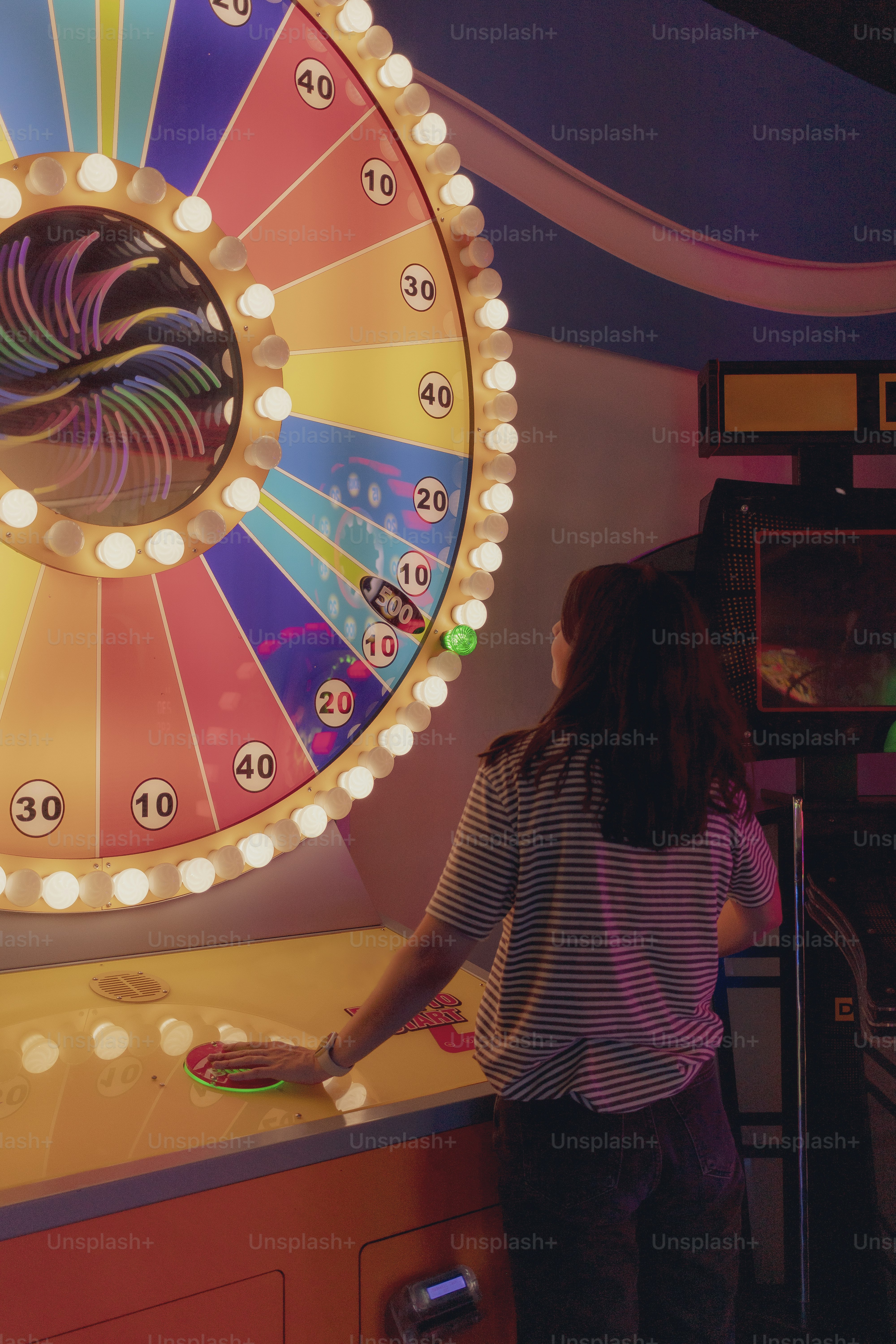 Woman plays the wheel of fortune game at an arcade.