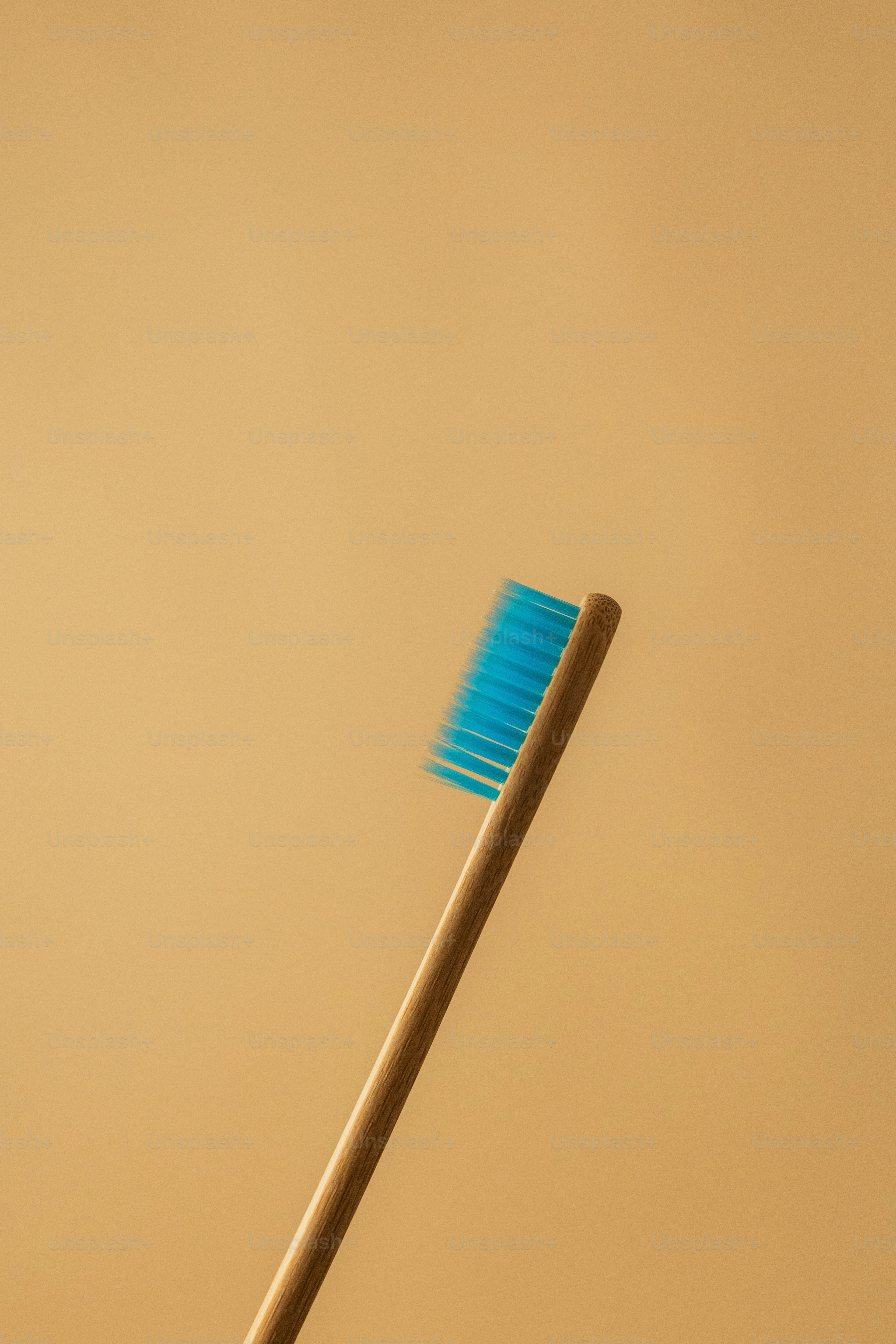 A blue-bristled toothbrush against a neutral backdrop.