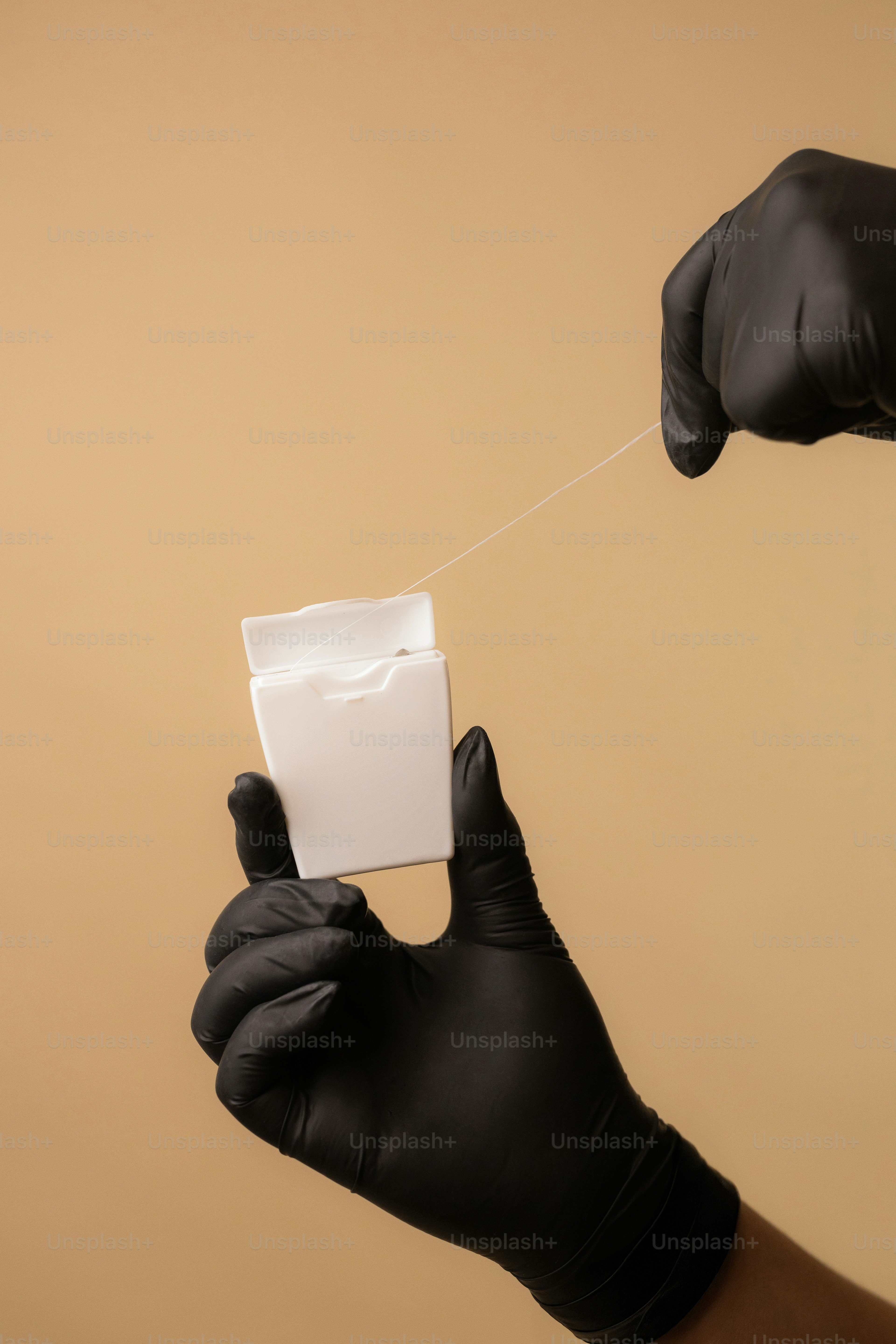 Hands in gloves use dental floss.