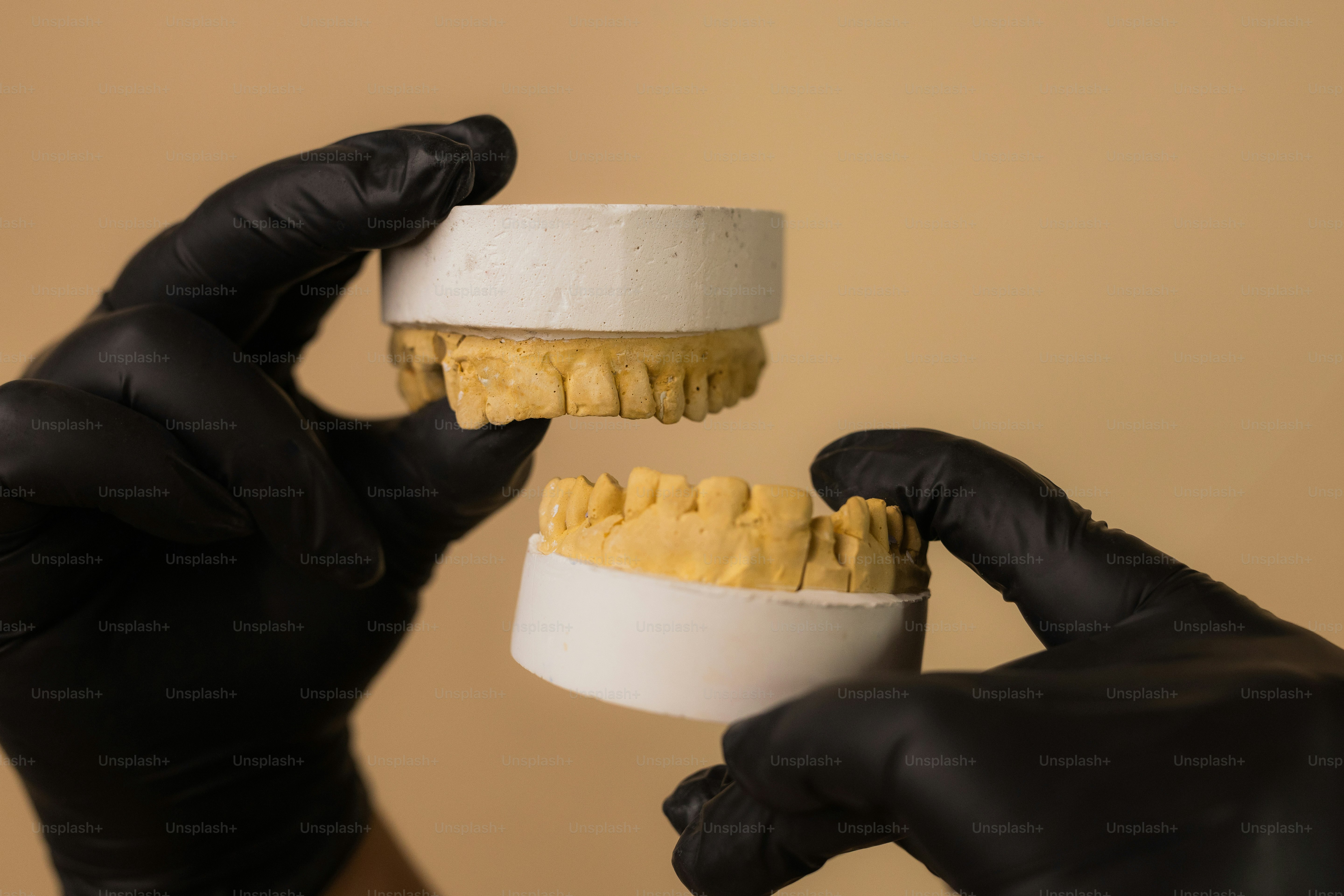 Hands in gloves holding a dental mold.