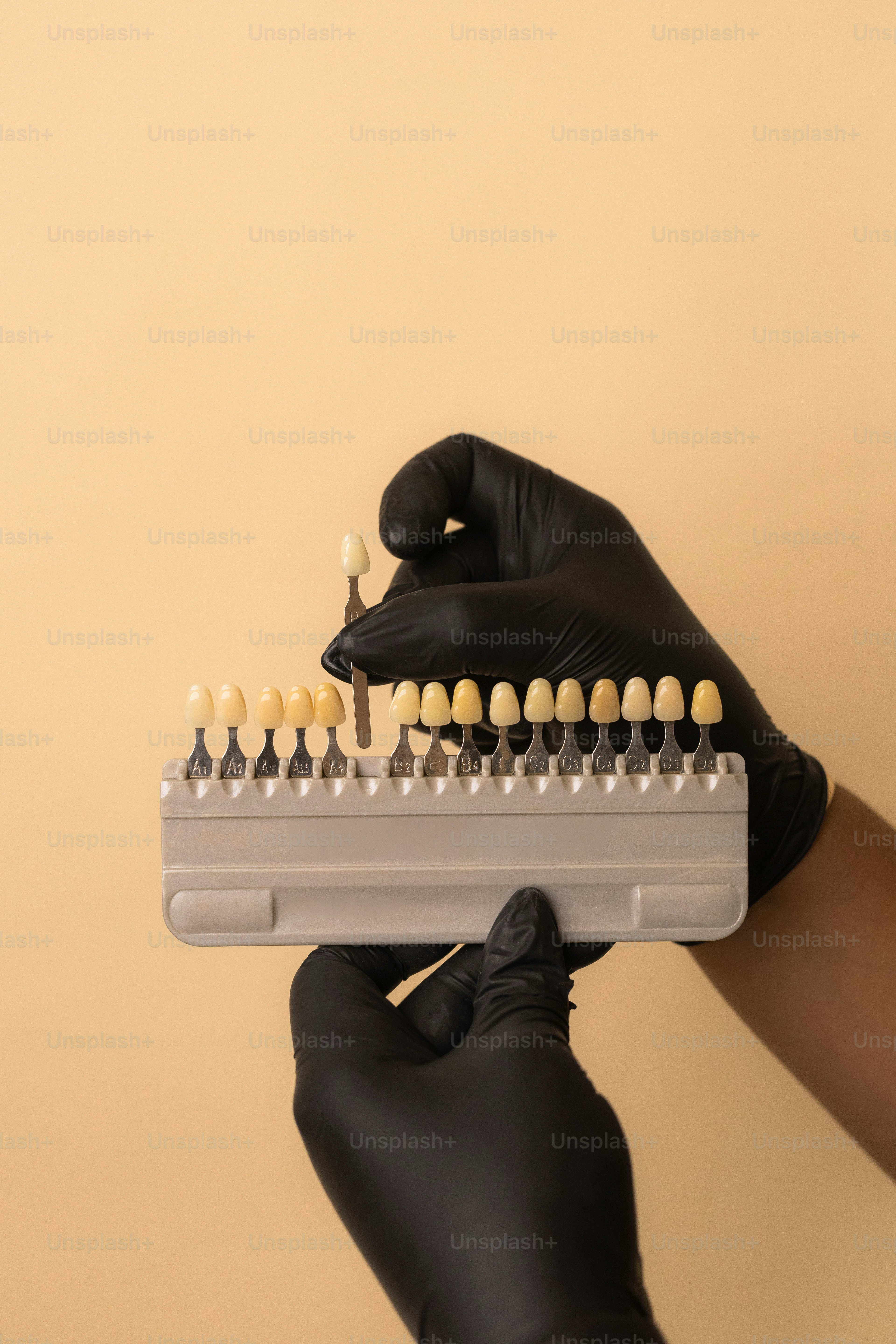 Dentist holding tooth shade guide with black gloves.