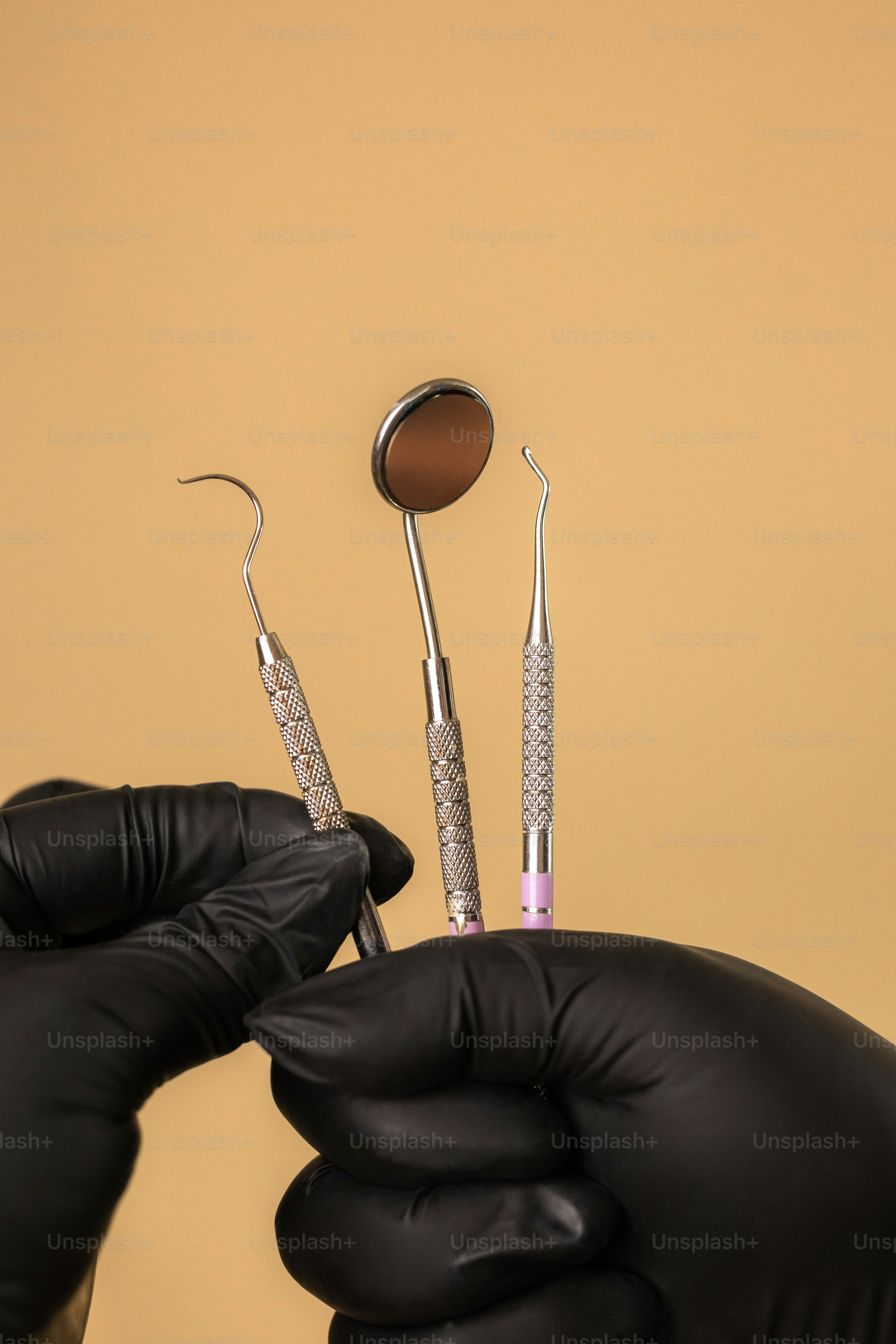 Hands in gloves holding dental tools.