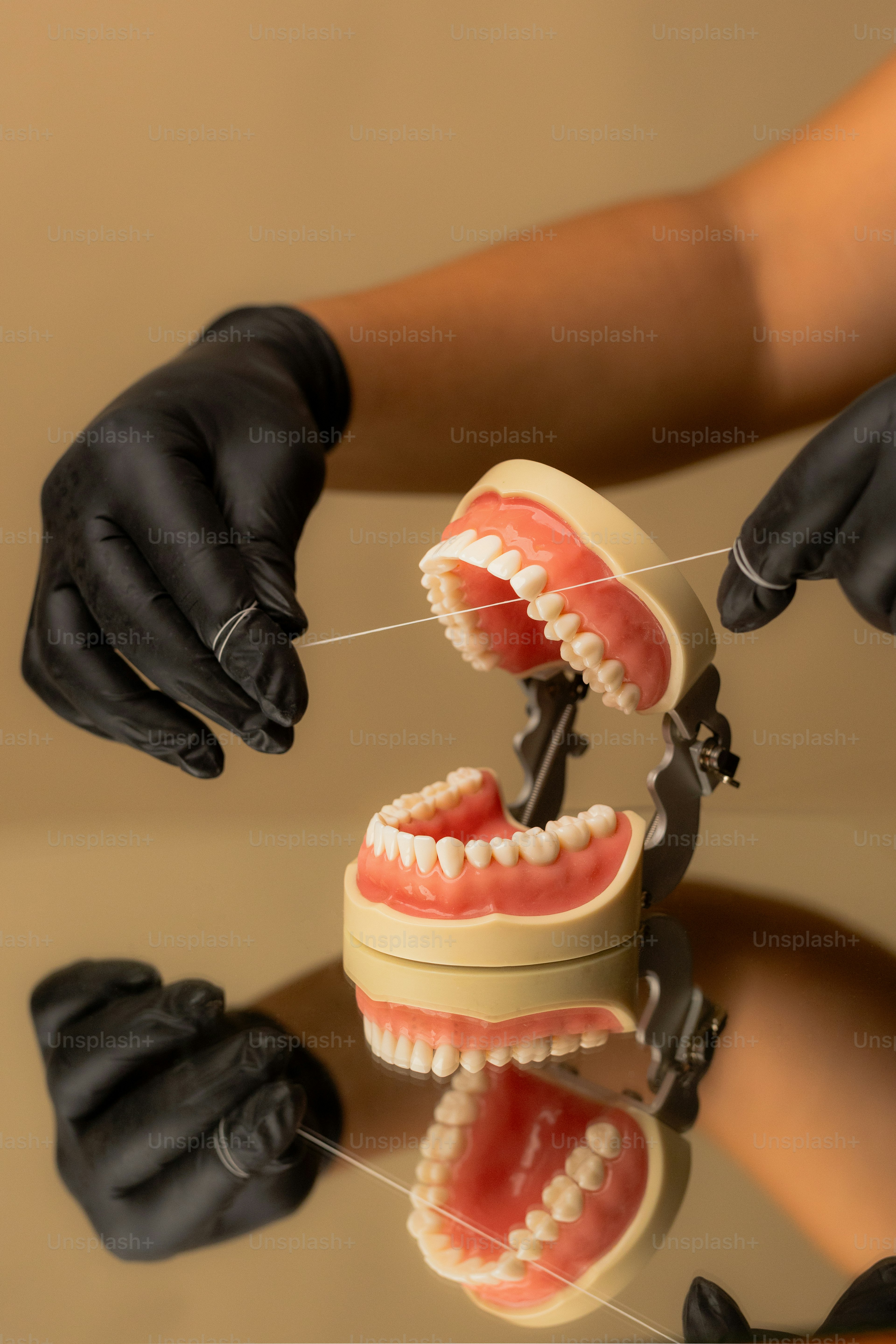 Las manos están usando hilo dental con guantes negros.