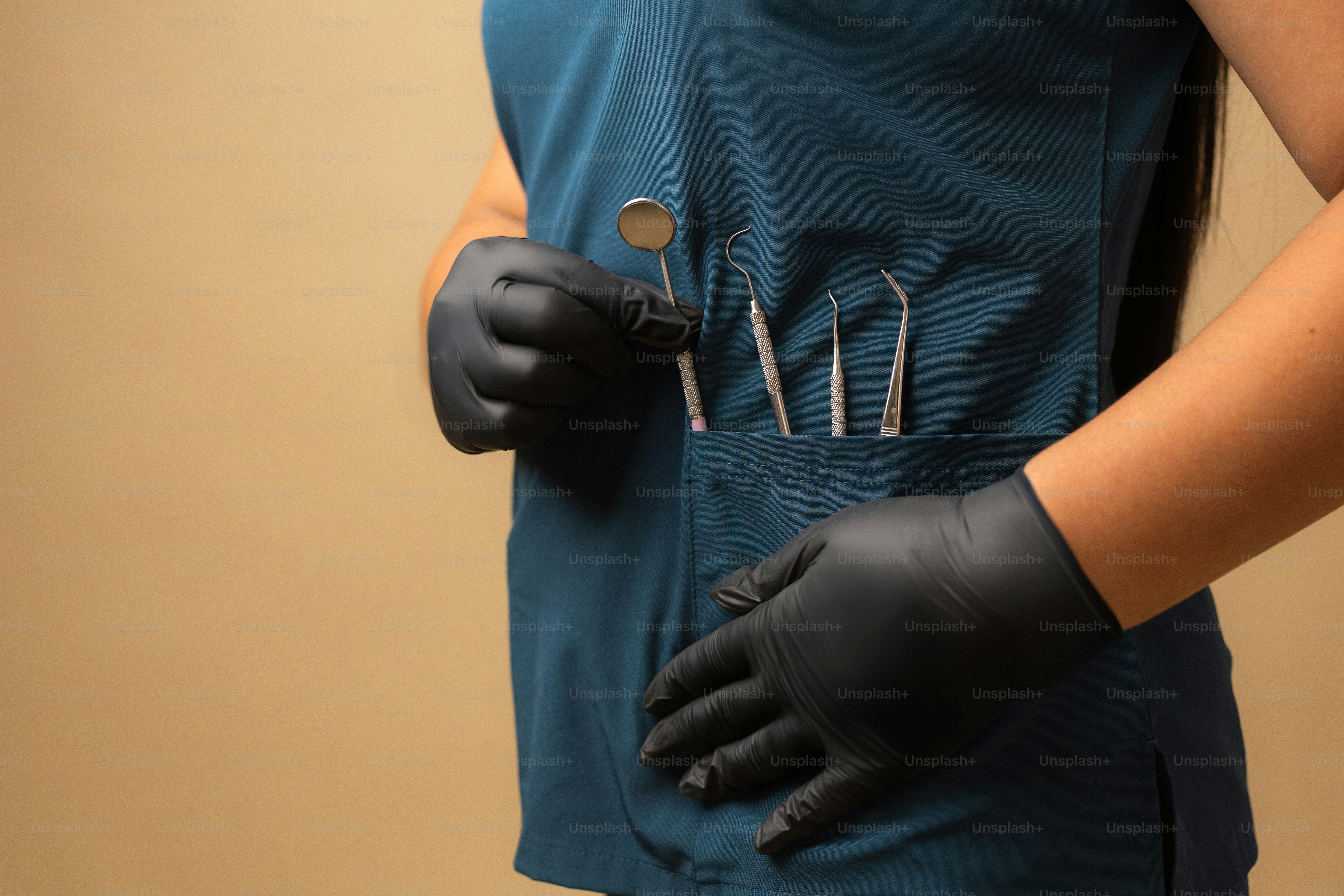 Zahnarzt trägt Handschuhe mit zahnärztlichen Werkzeugen.