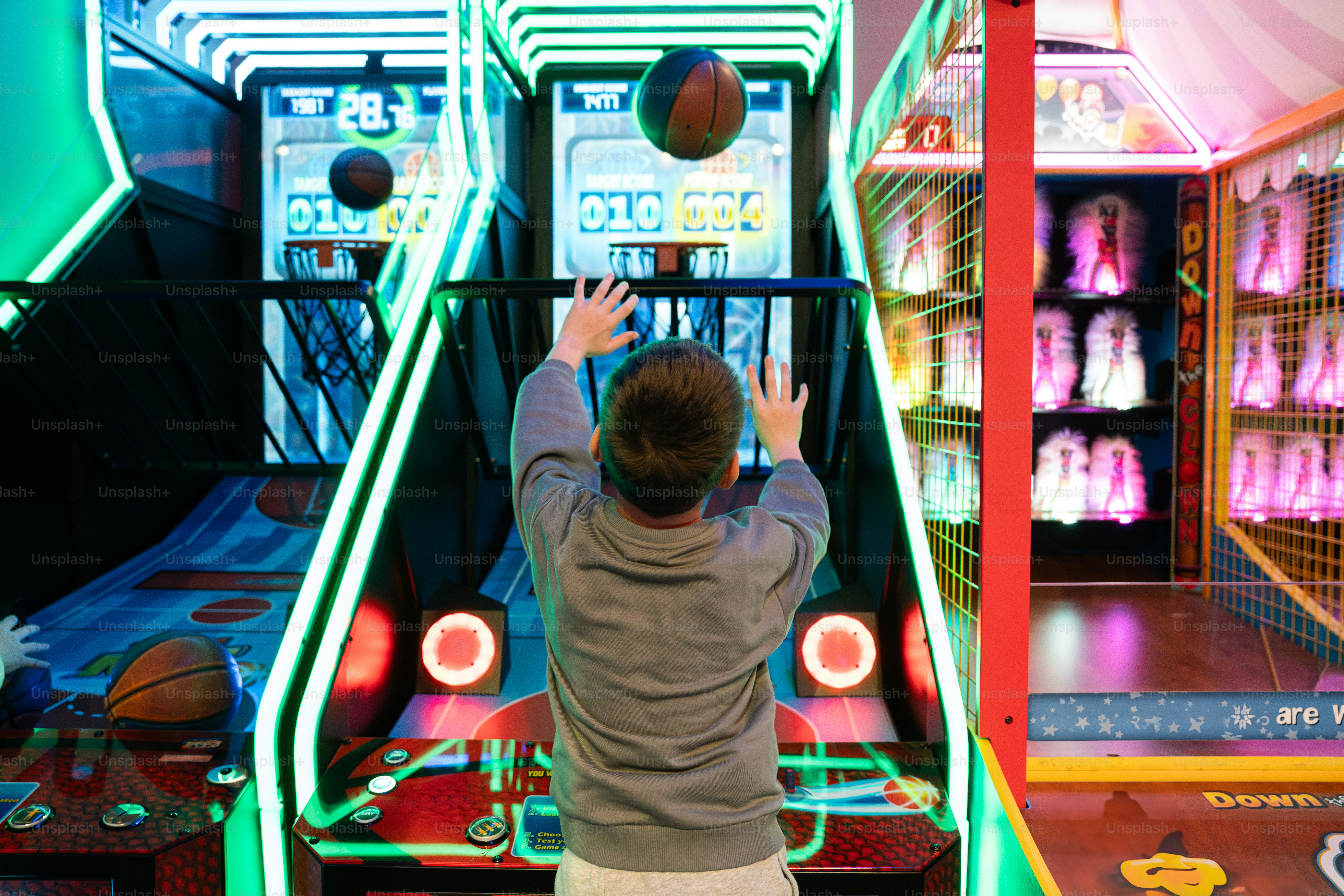 Boy plays basketball arcade game.
