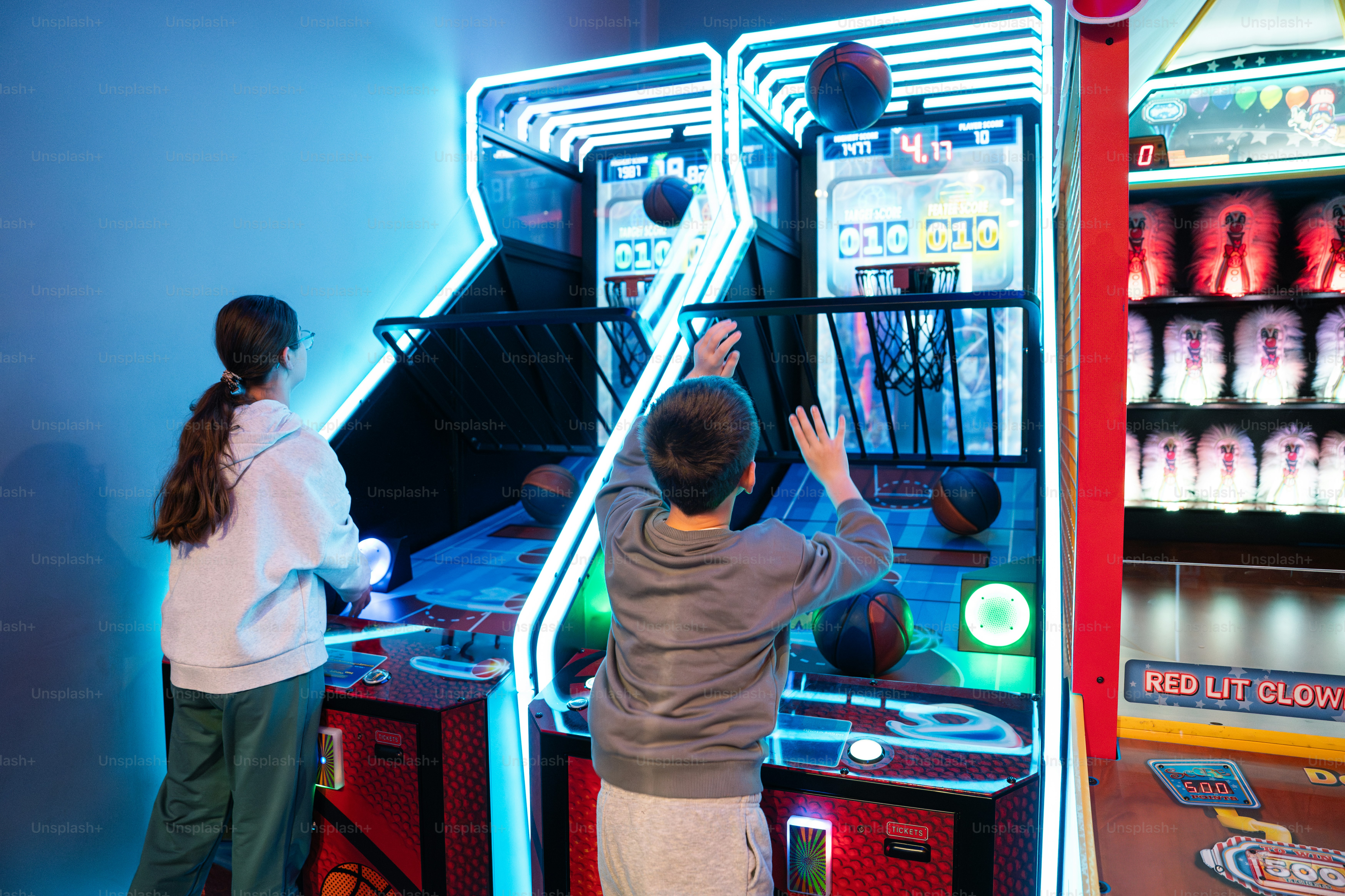Les enfants jouent à un jeu d’arcade de basket-ball.