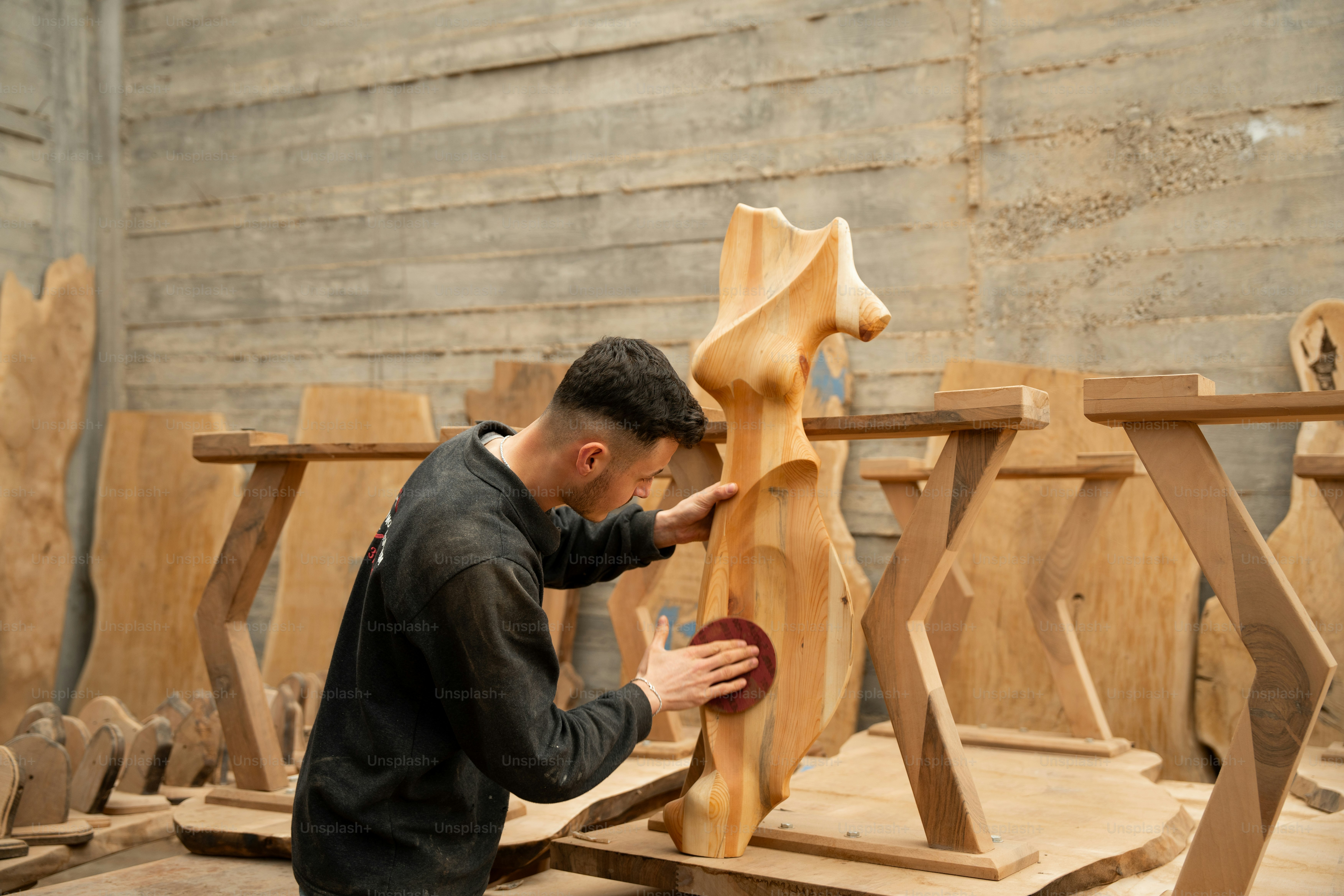 A man is sanding a wooden sculpture.