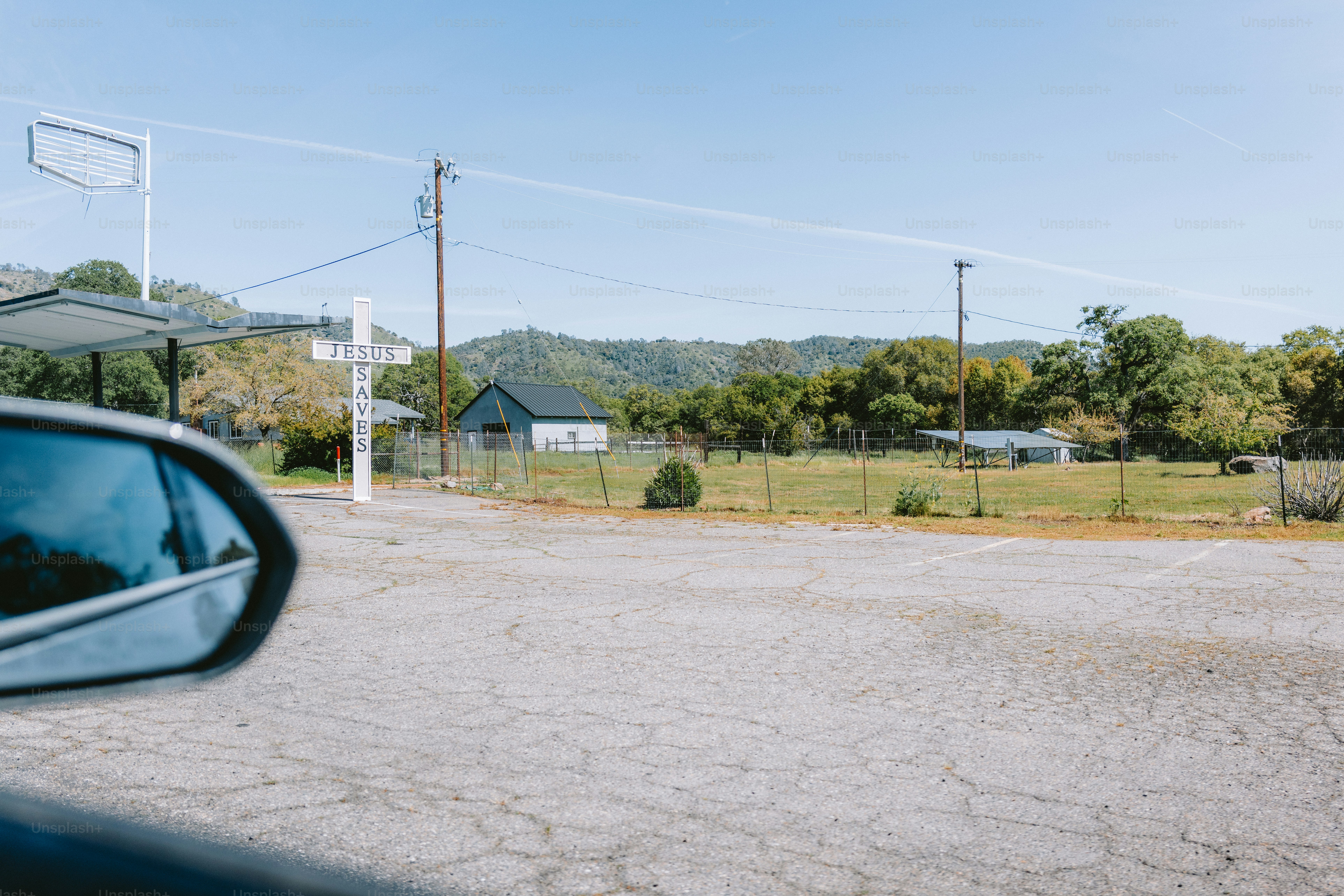 A rural scene is viewed from a car.