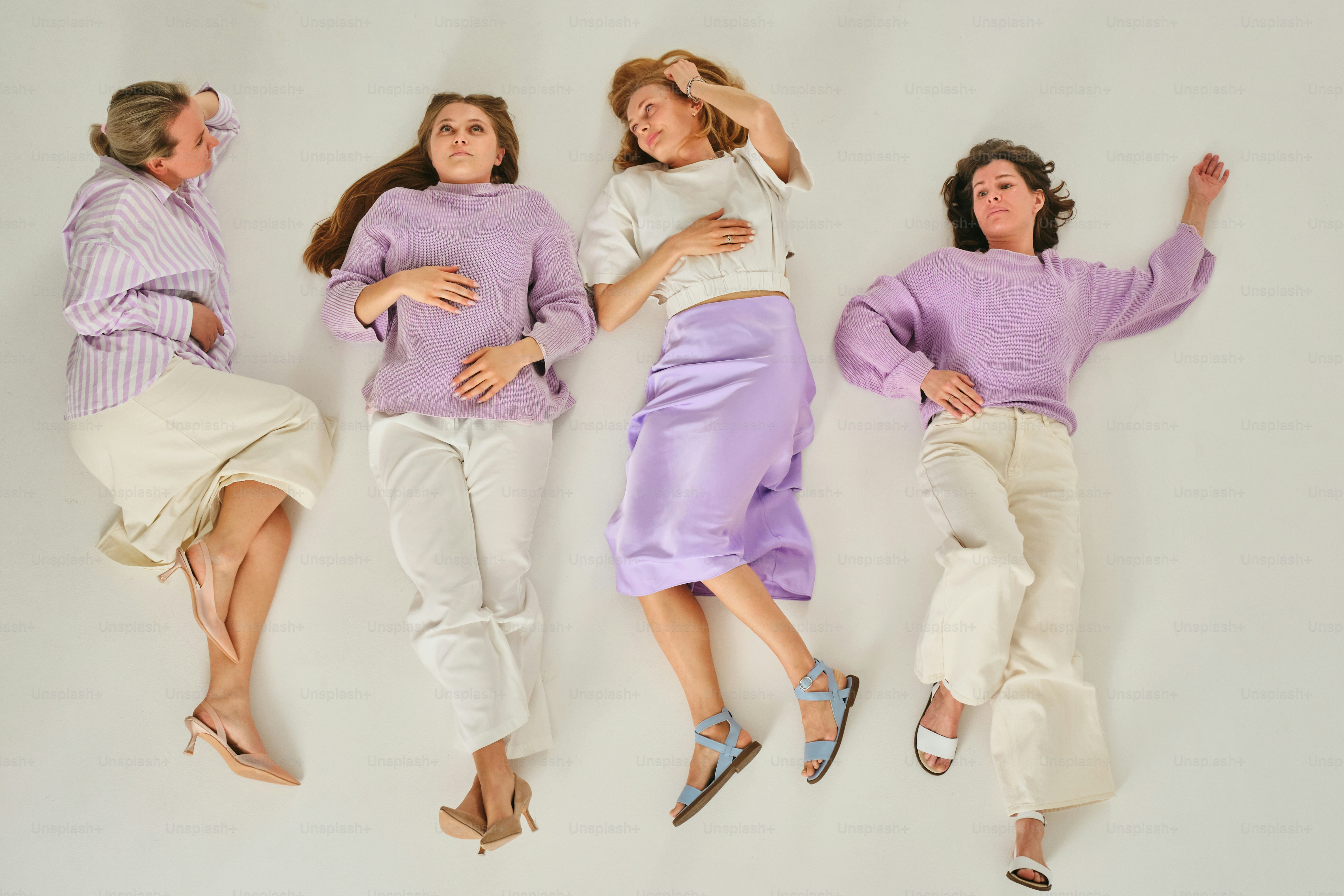 Cuatro mujeres posan casualmente en el suelo.