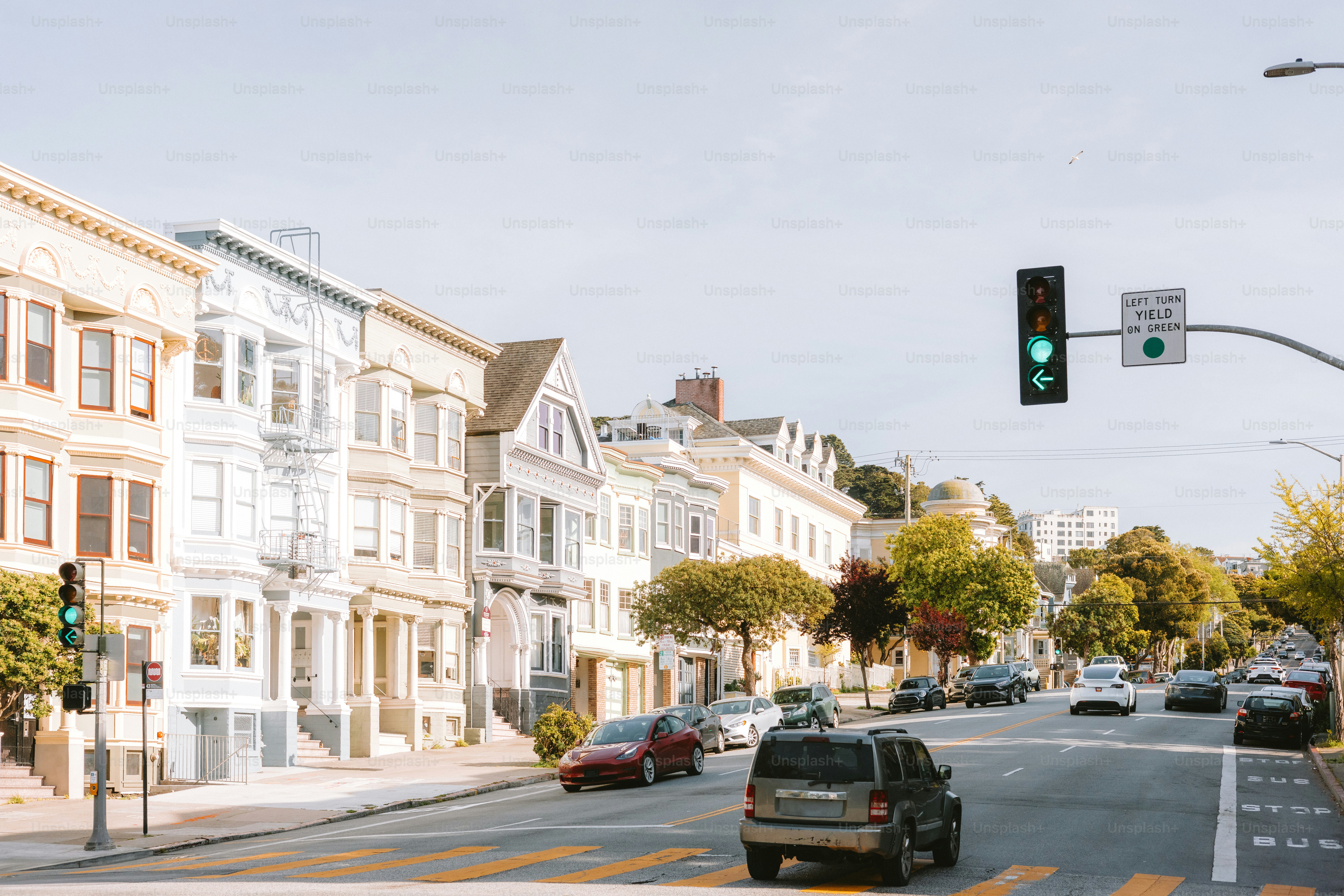 Houses line a sunny street with cars.