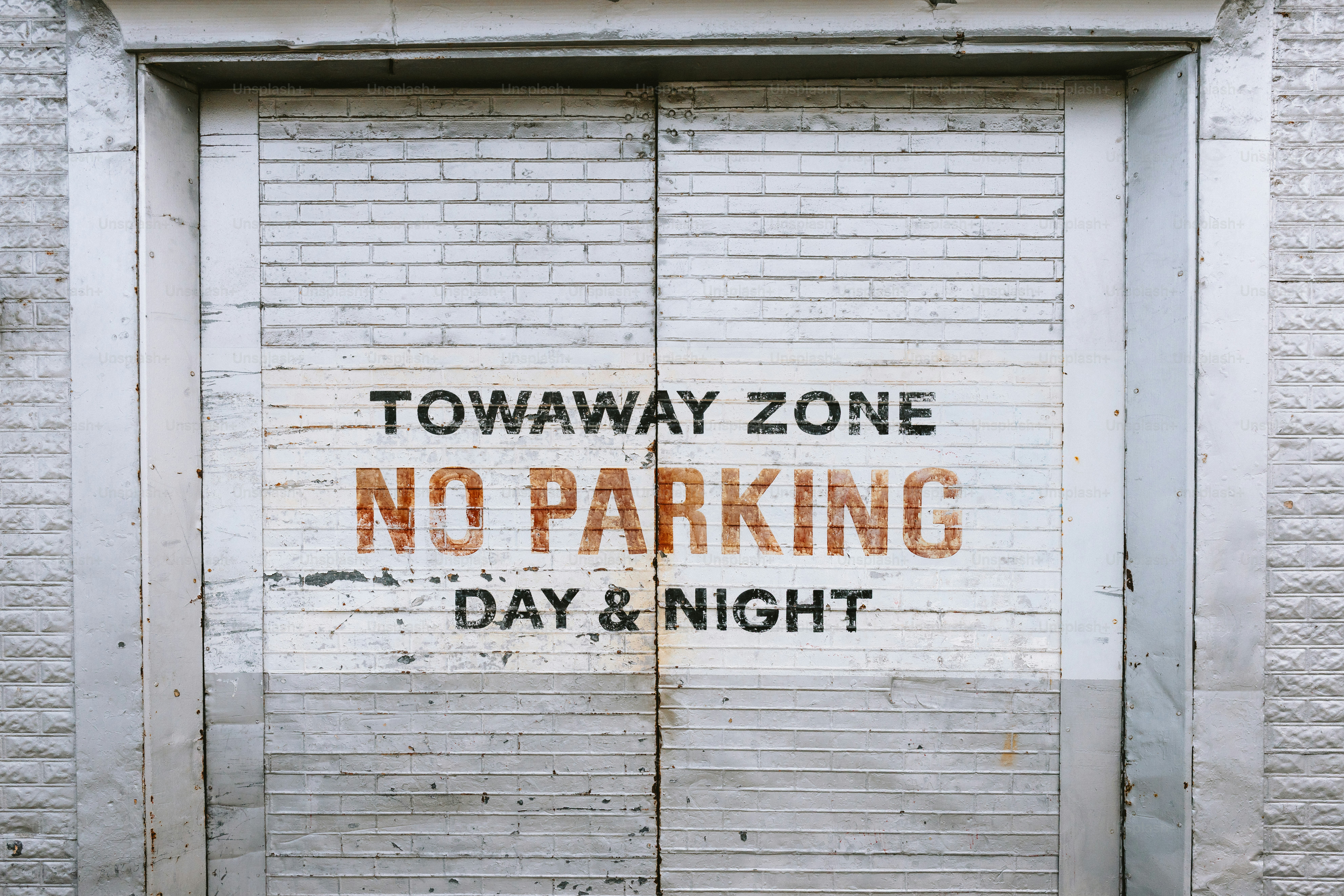 Señal de no estacionamiento en una puerta de garaje desgastada.