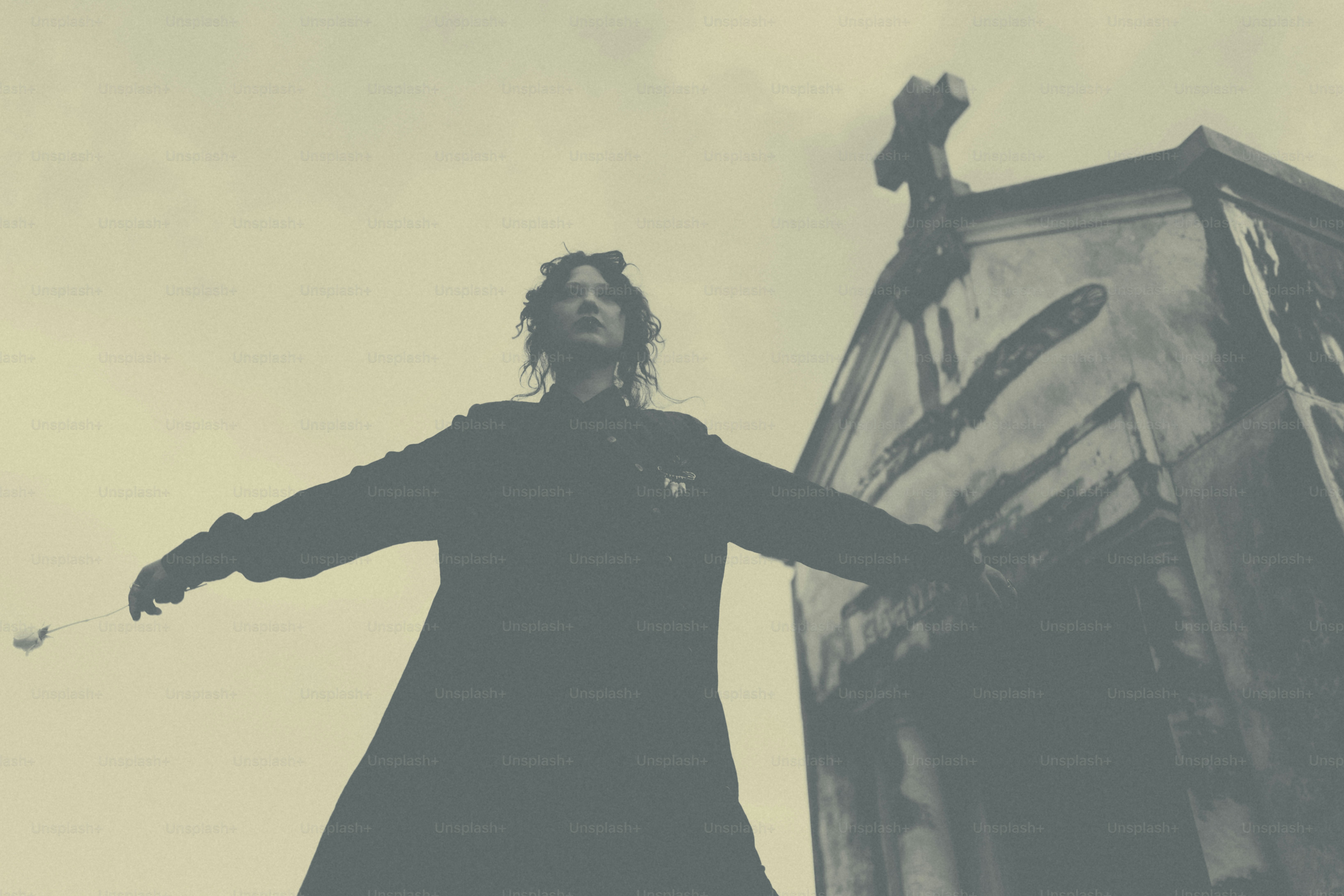 Gothic figure stands before a tomb in the cemetery.