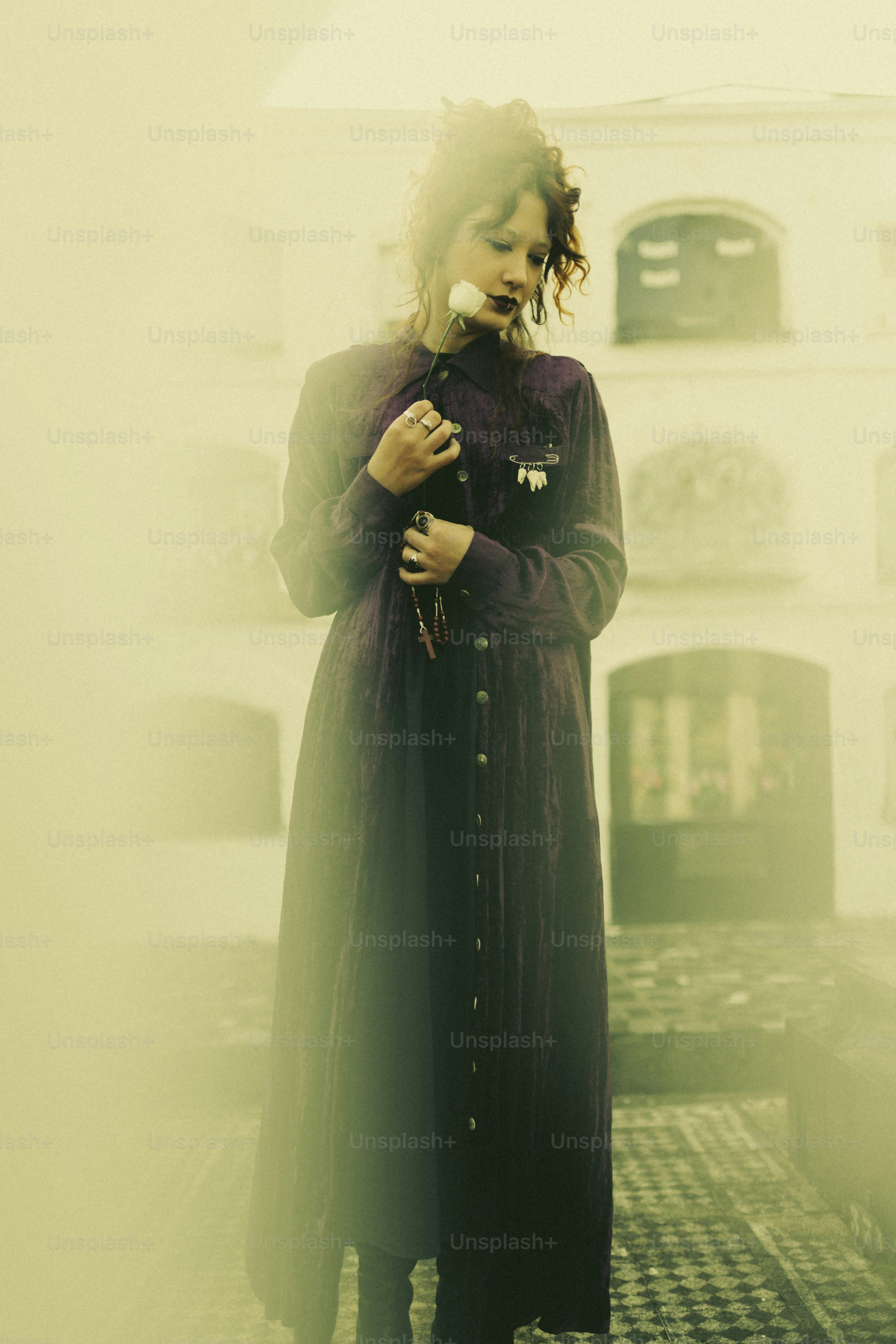 A woman holds a flower, lost in thought.