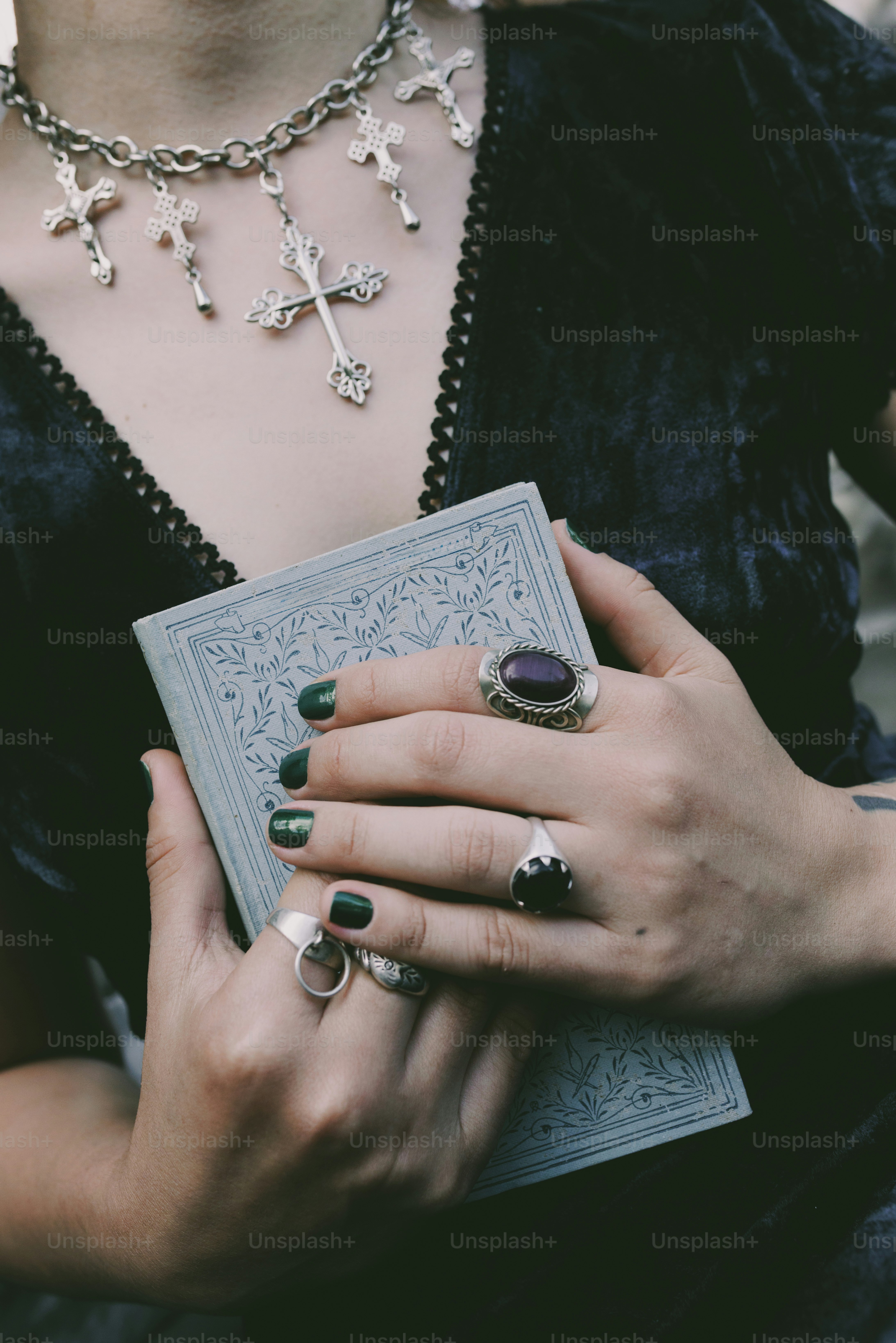 A person holds a book with elegant jewelry.