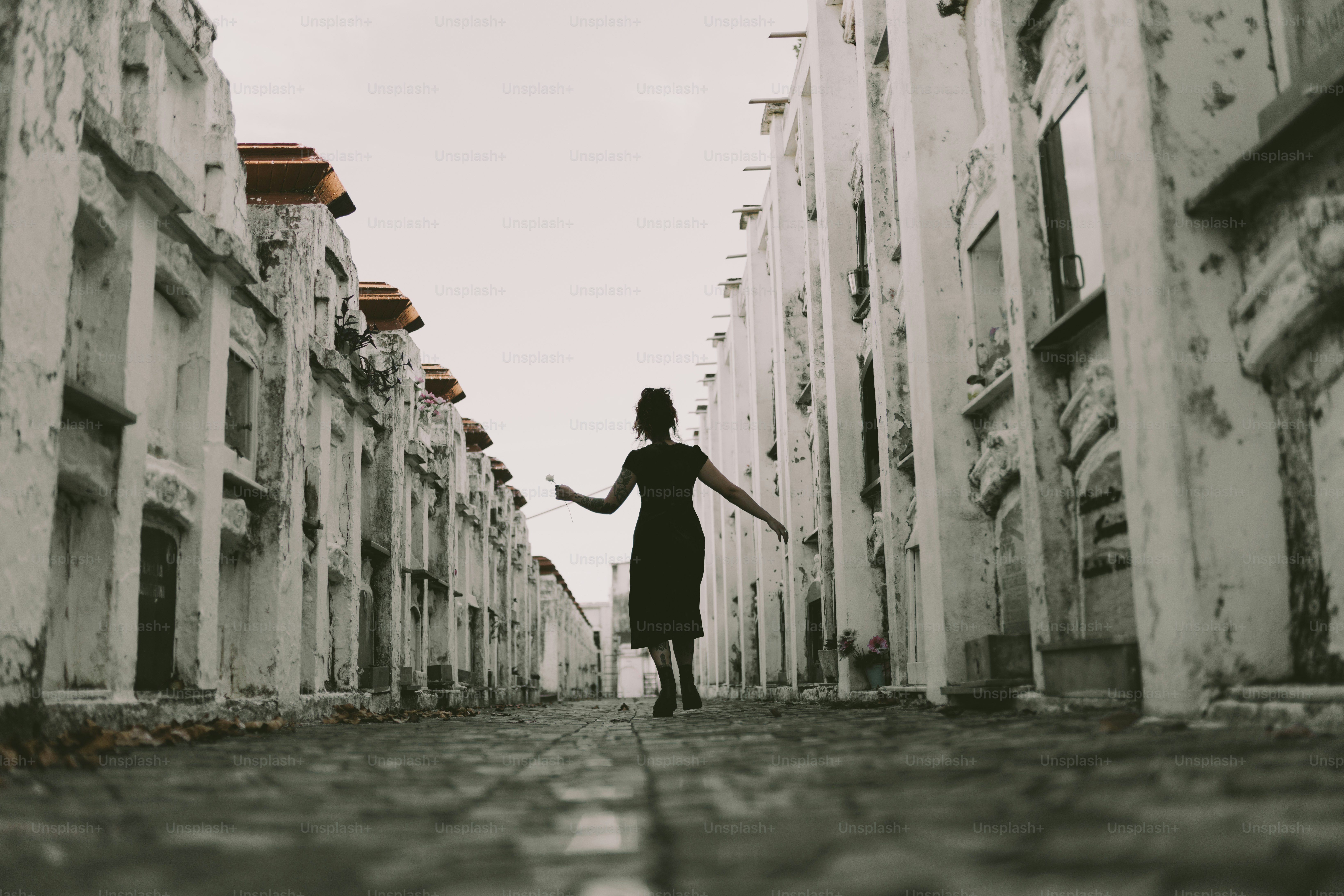 A woman walks down a white alley.
