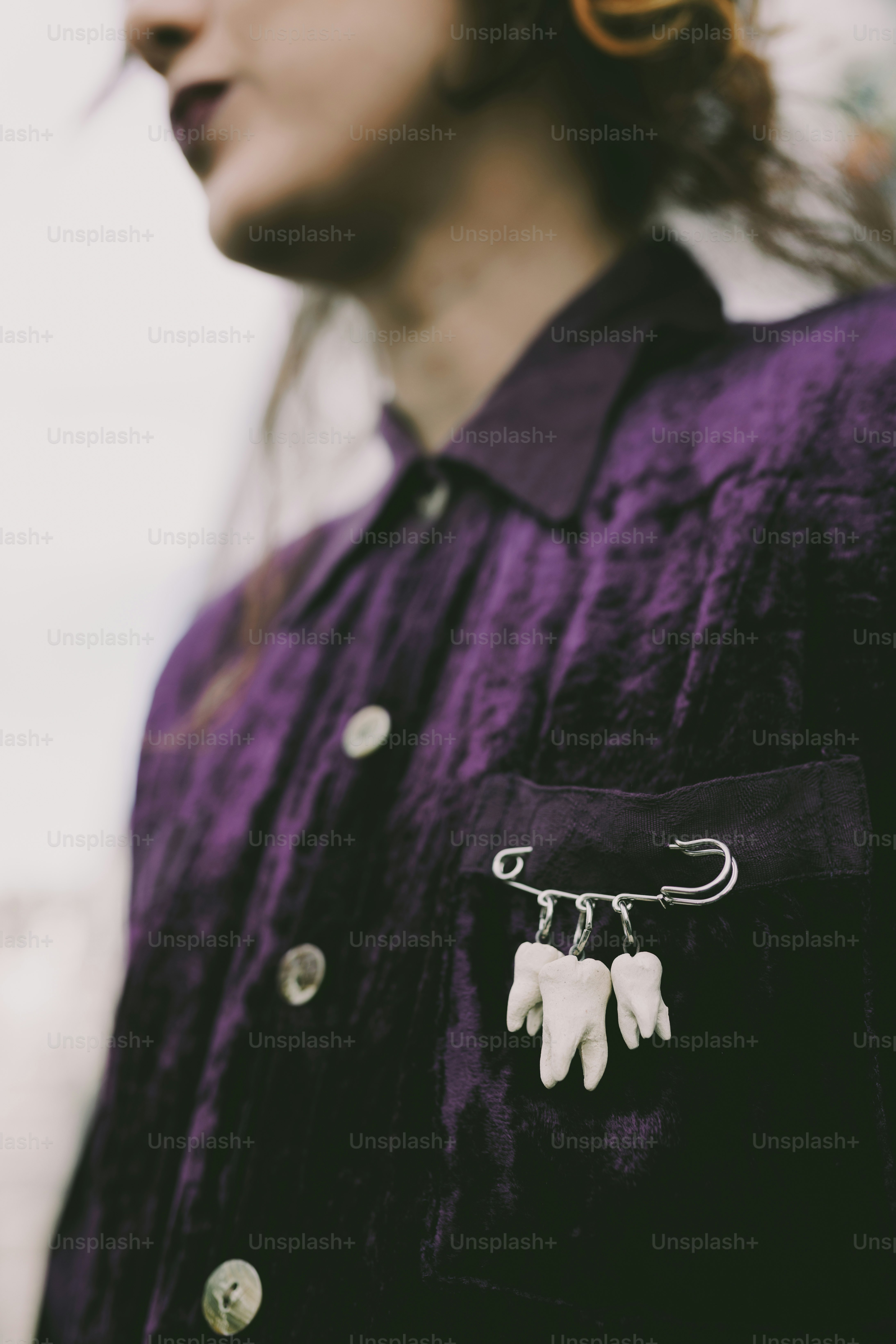 紫色のシャツに歯のピンを留めた女性。