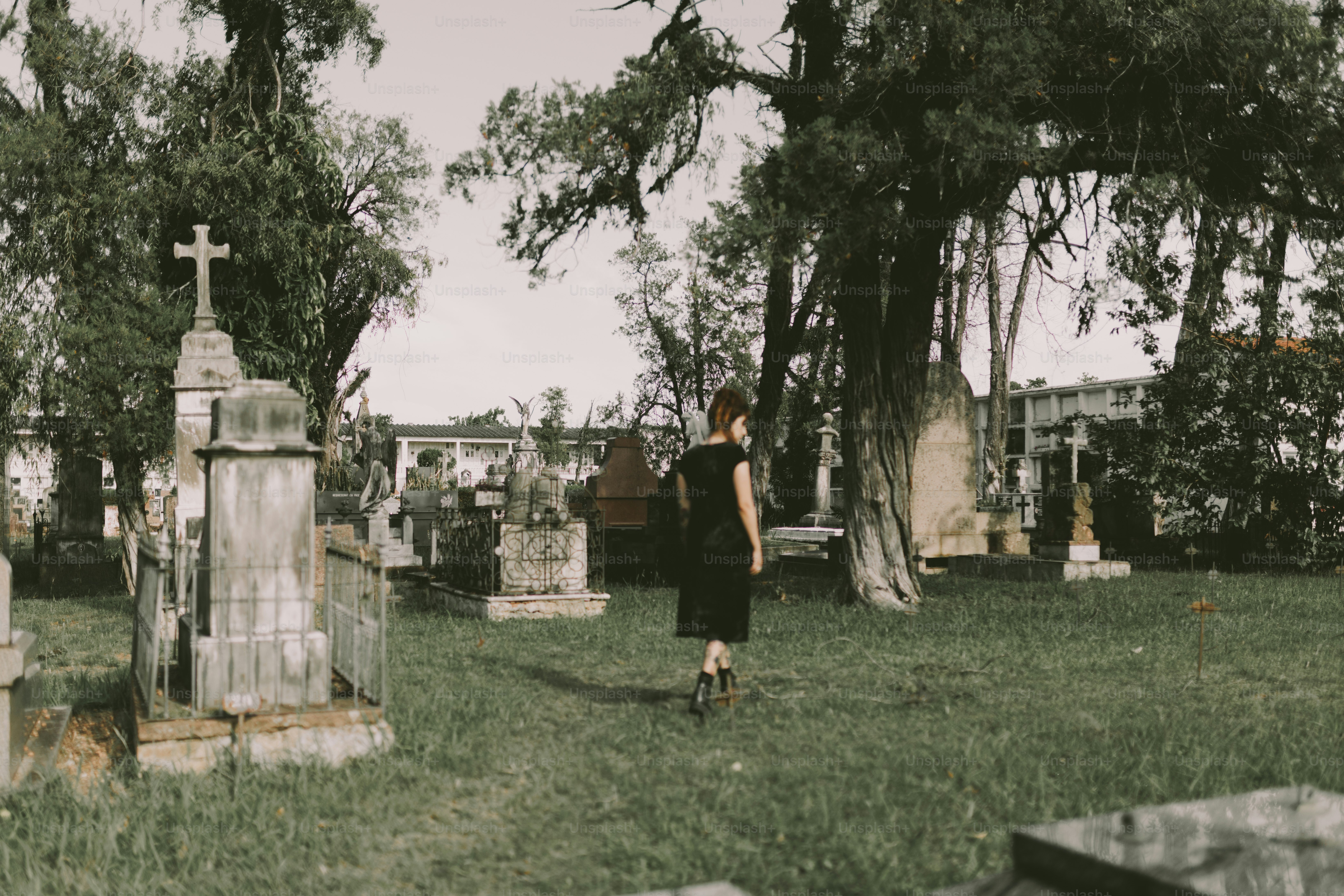 A woman walks through a serene cemetery.
