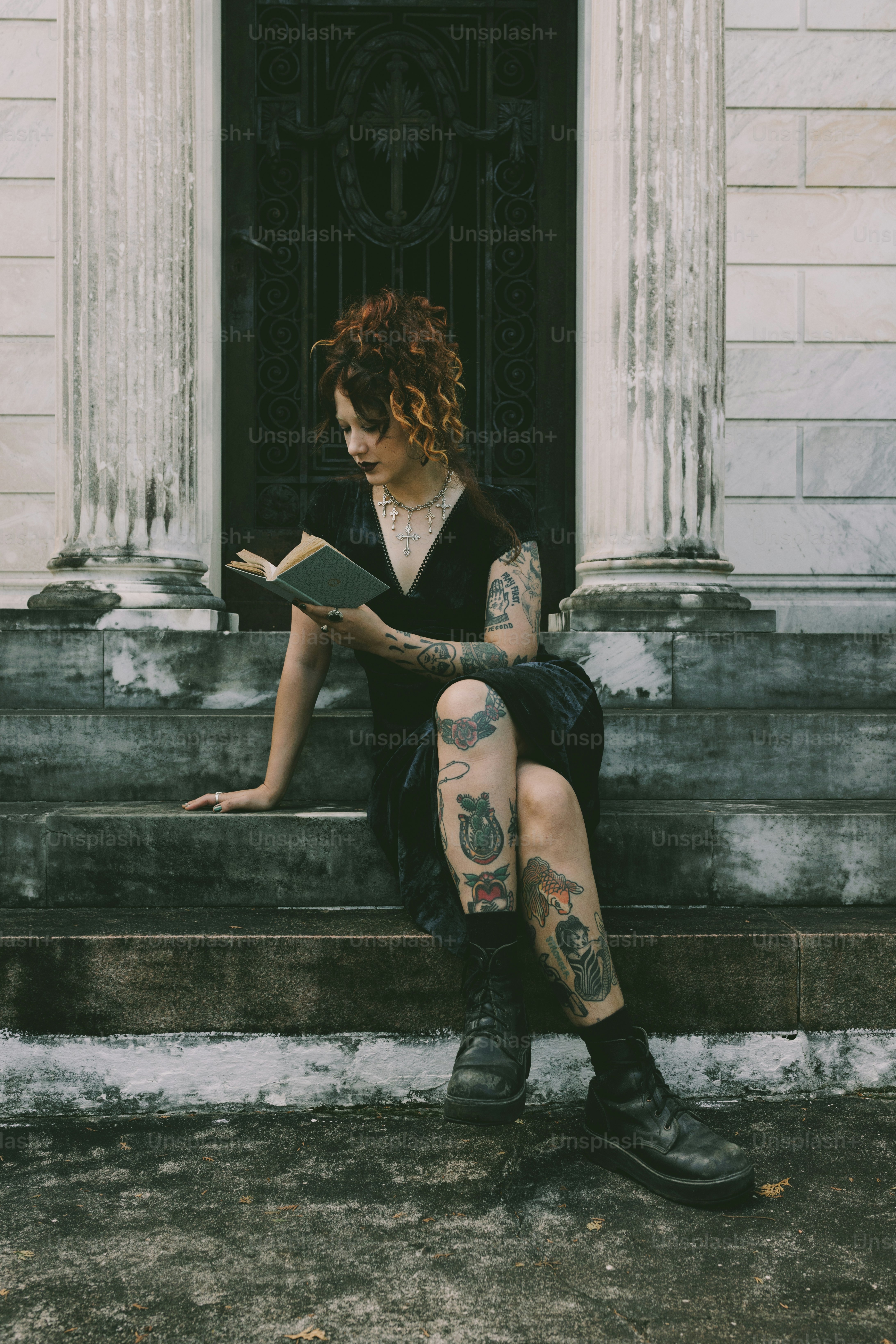 A woman reads a book on steps.