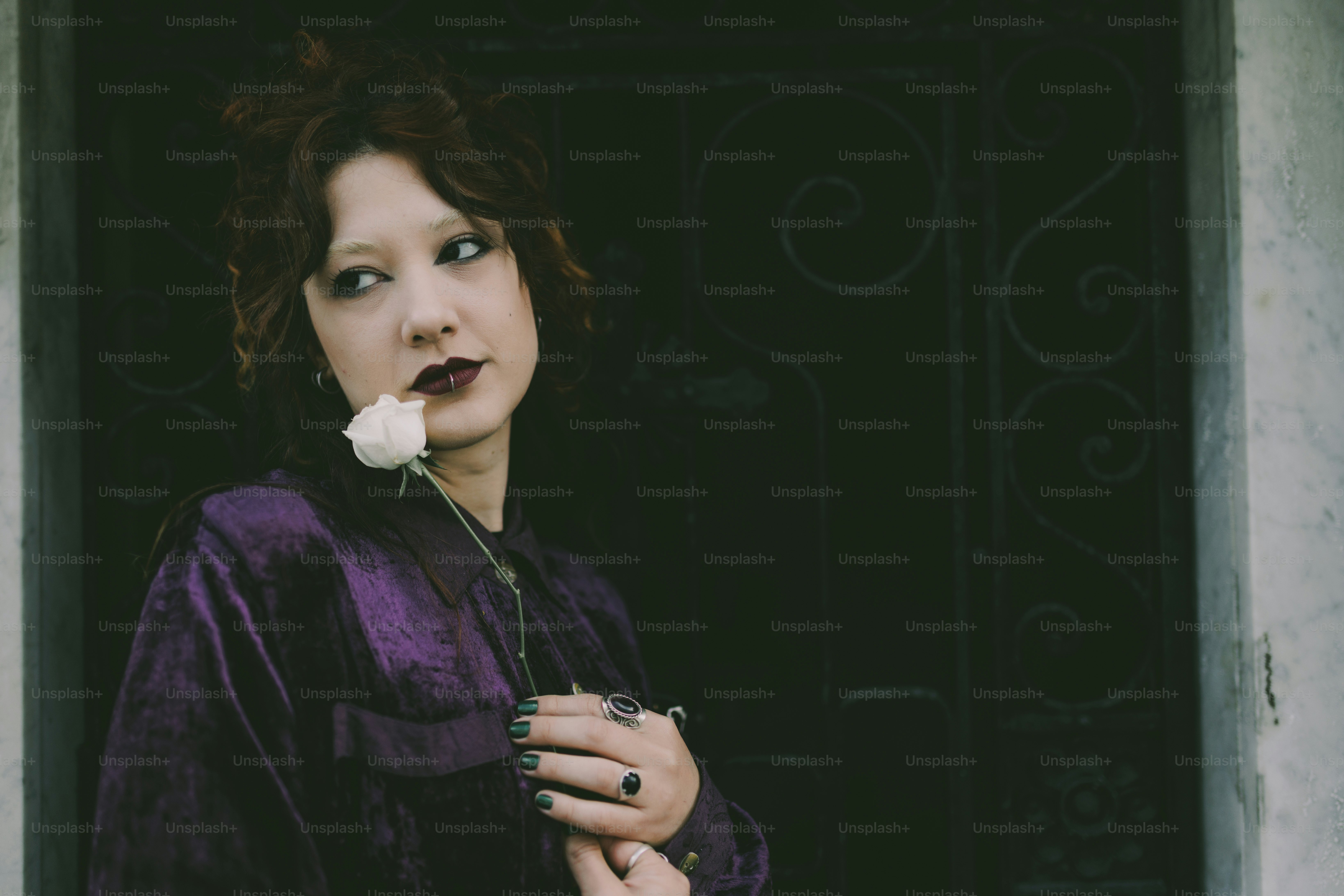 A woman in purple holds a white rose.