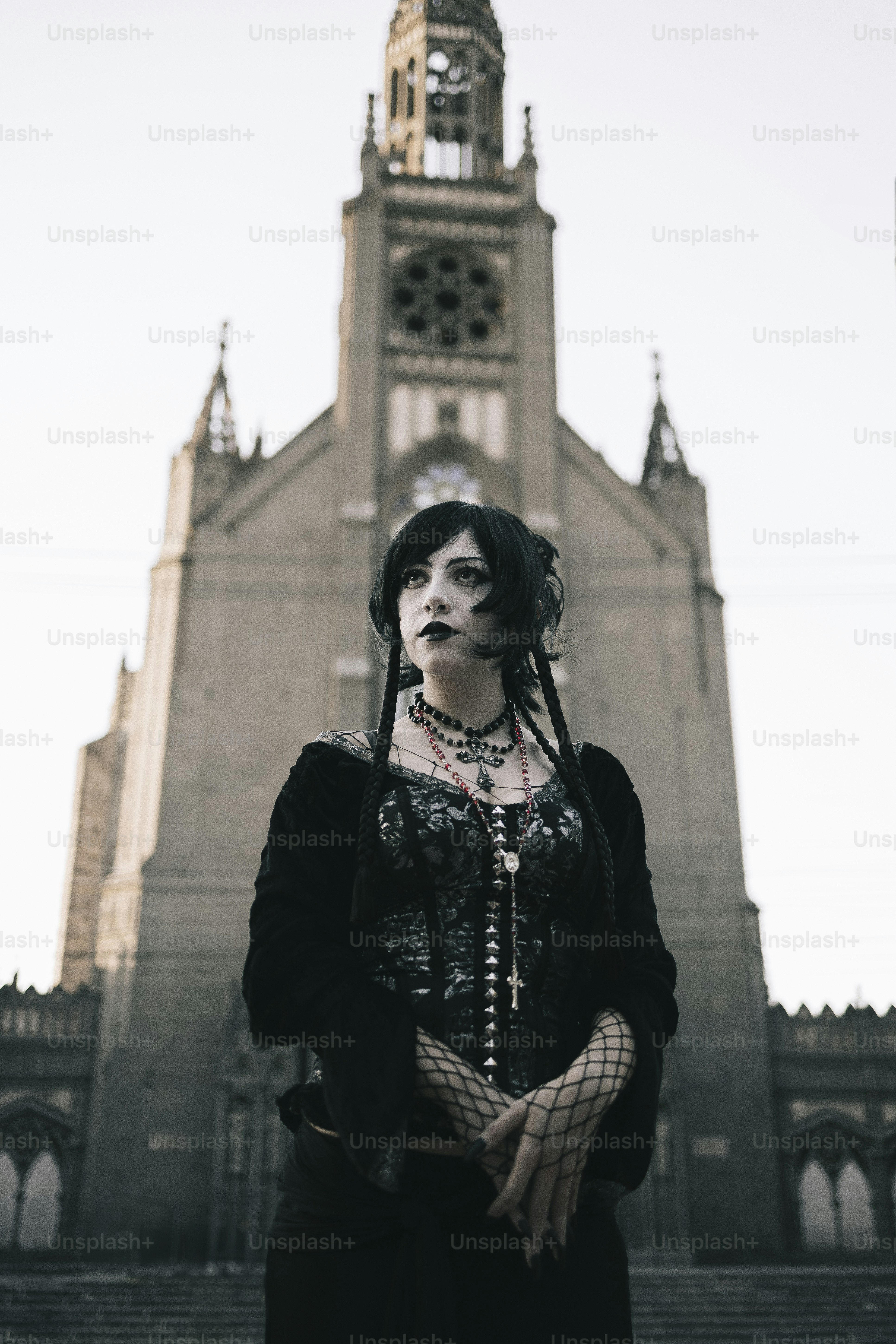 A gothic woman stands before a grand church.