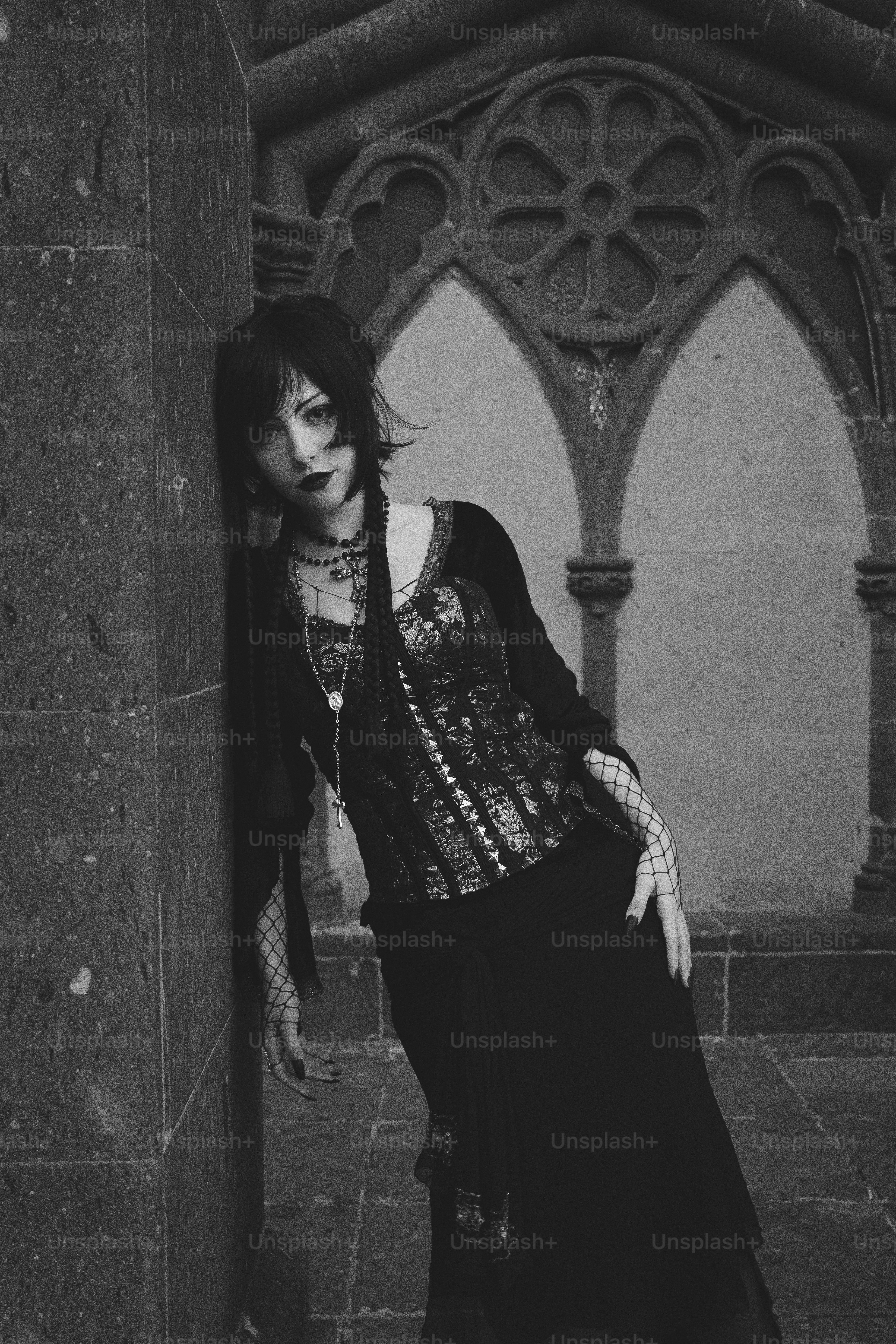 Eine Gothic-Frau lehnt sich an eine Kirche.