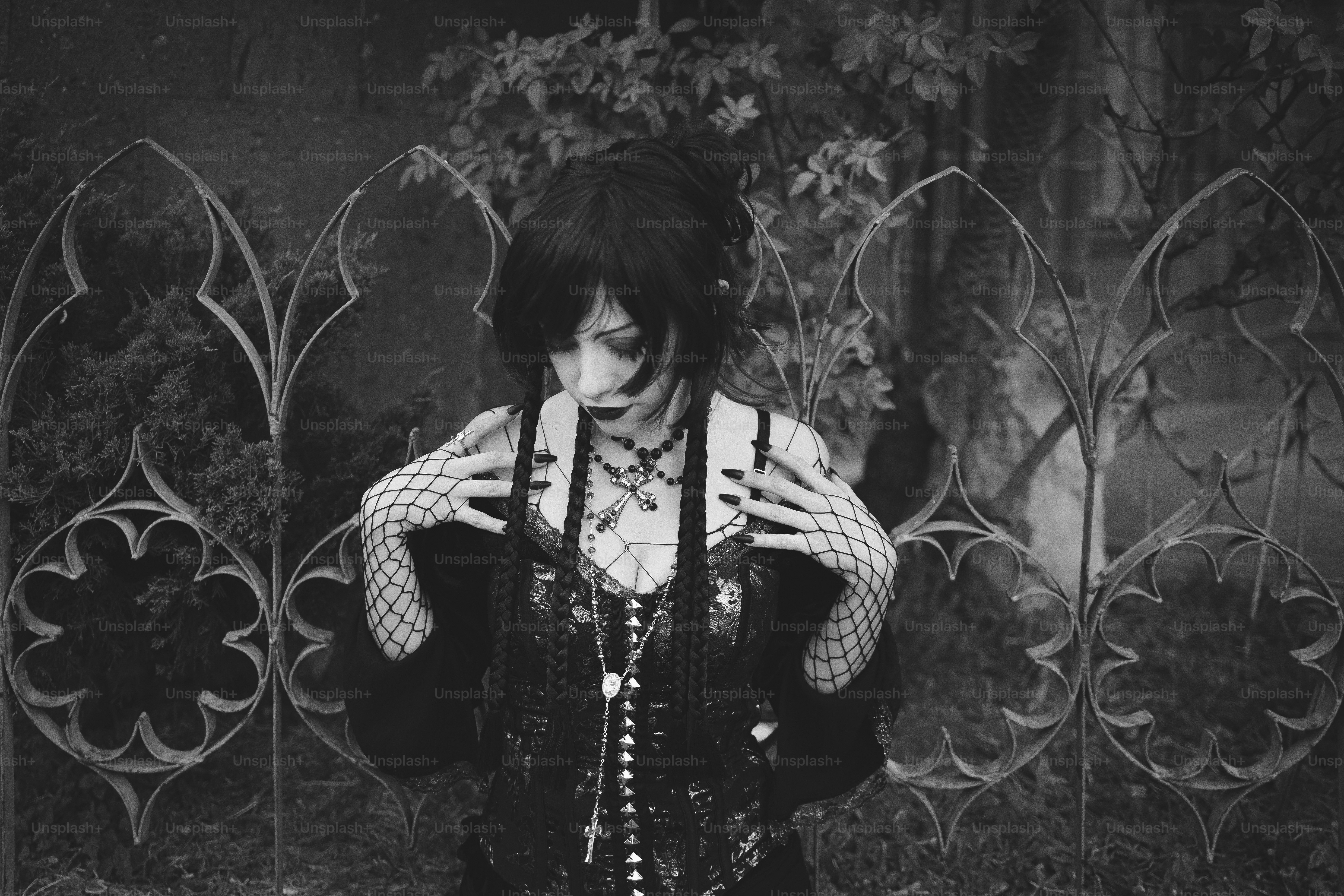 A gothic woman poses near a decorative gate.