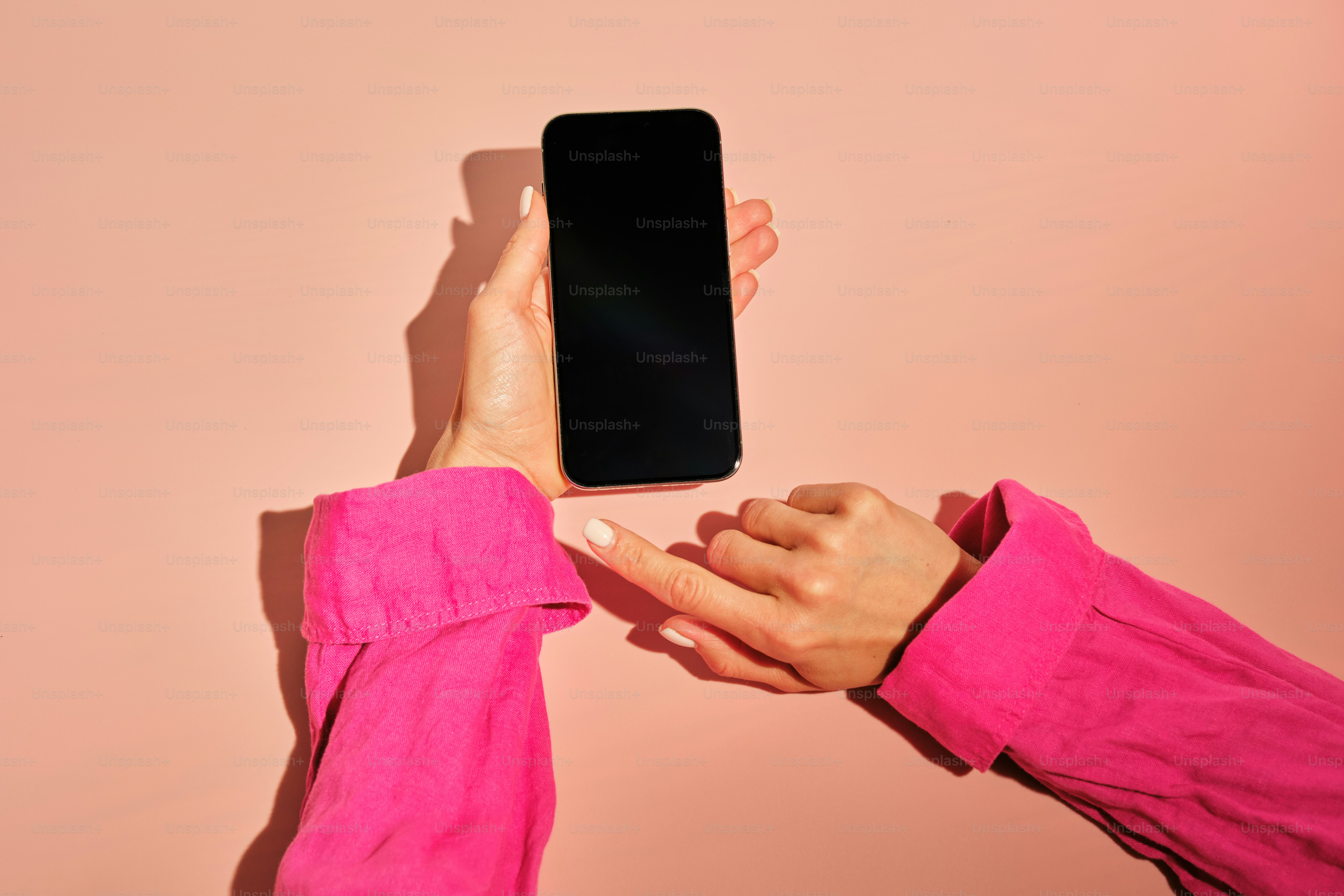 女性は電話を持ち、画面を指差しています。