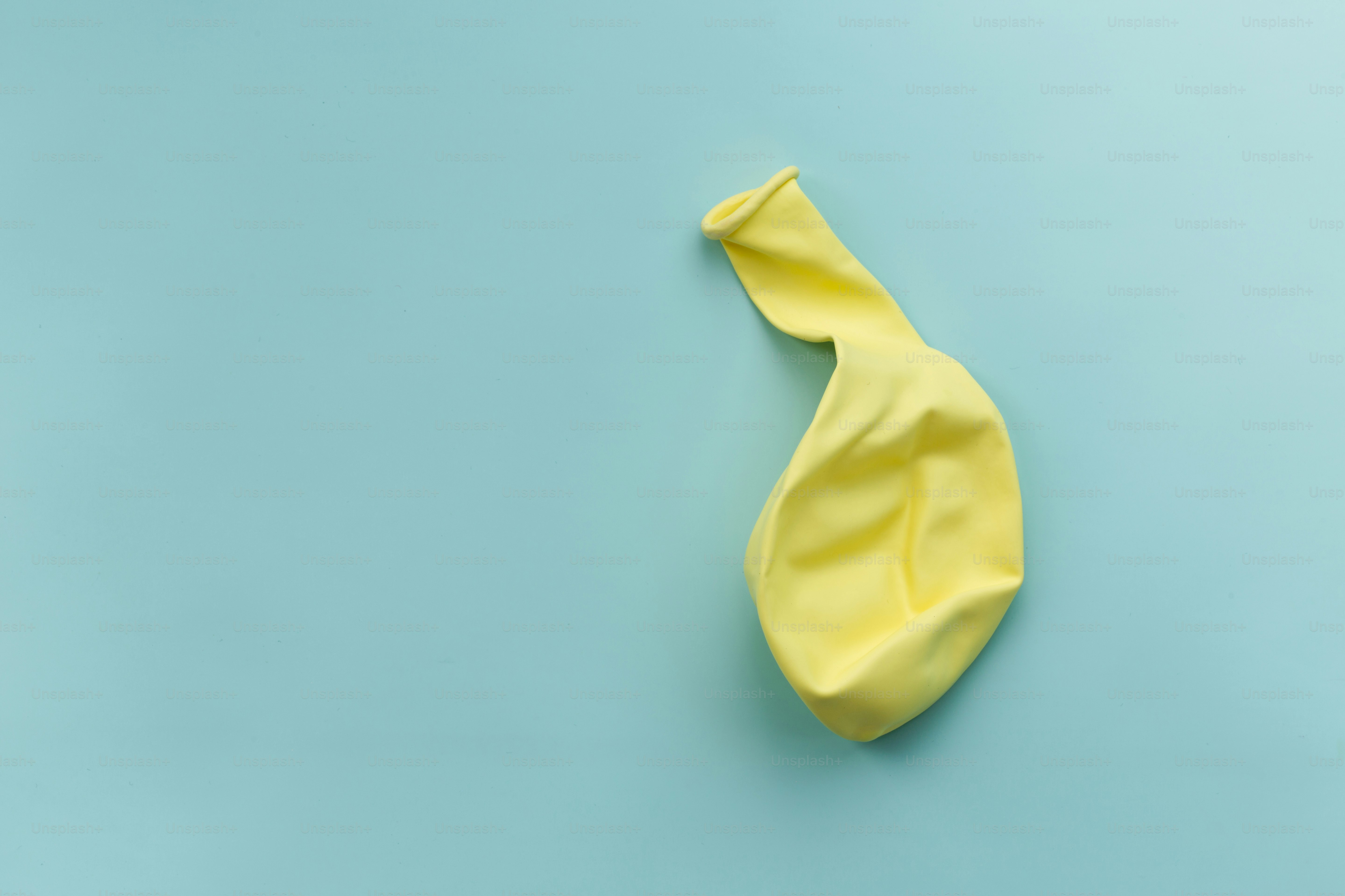 Ein entleerter gelber Ballon liegt auf einer blauen Fläche.