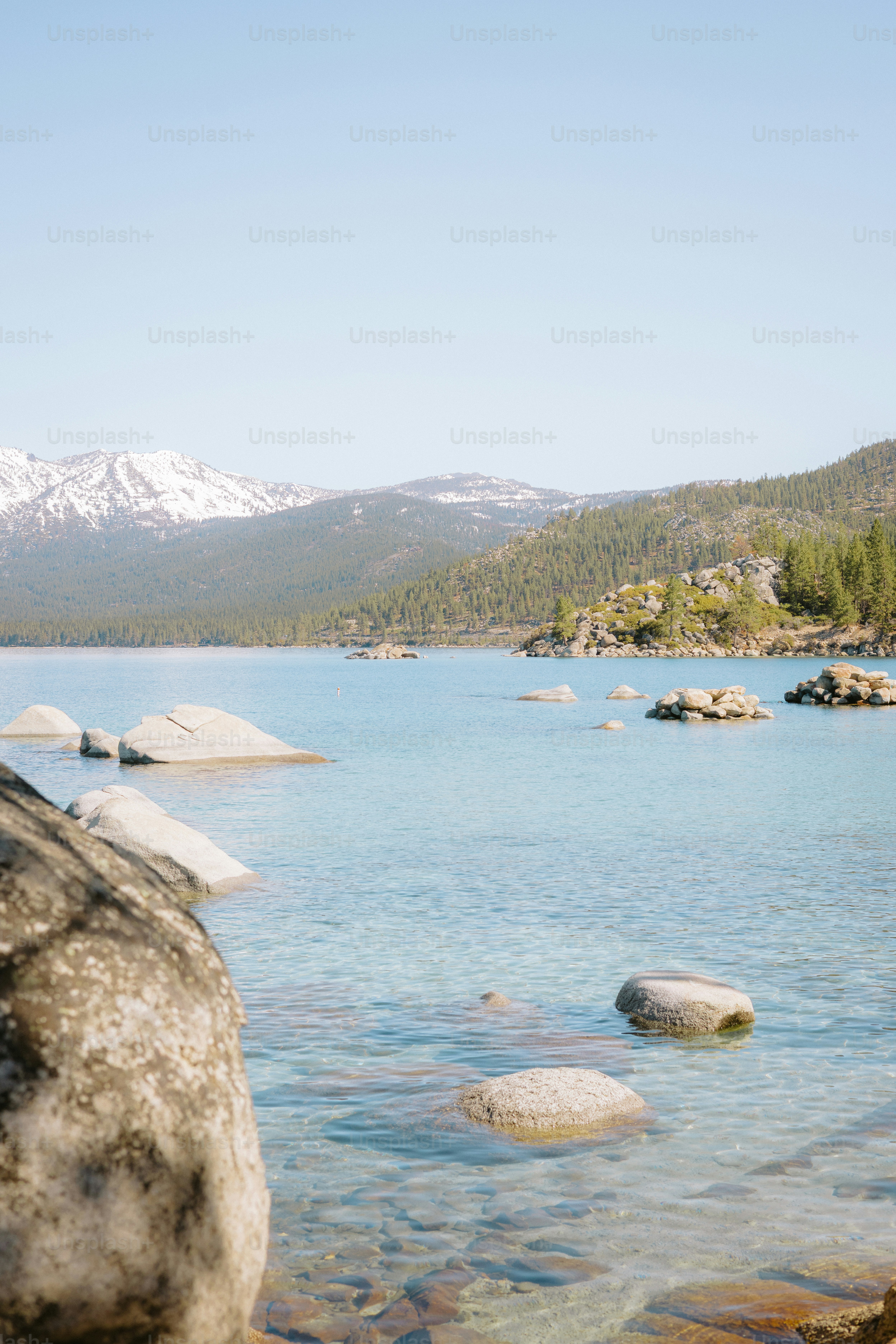 Schöner türkisfarbener See mit Felsen und Bergkulisse.
