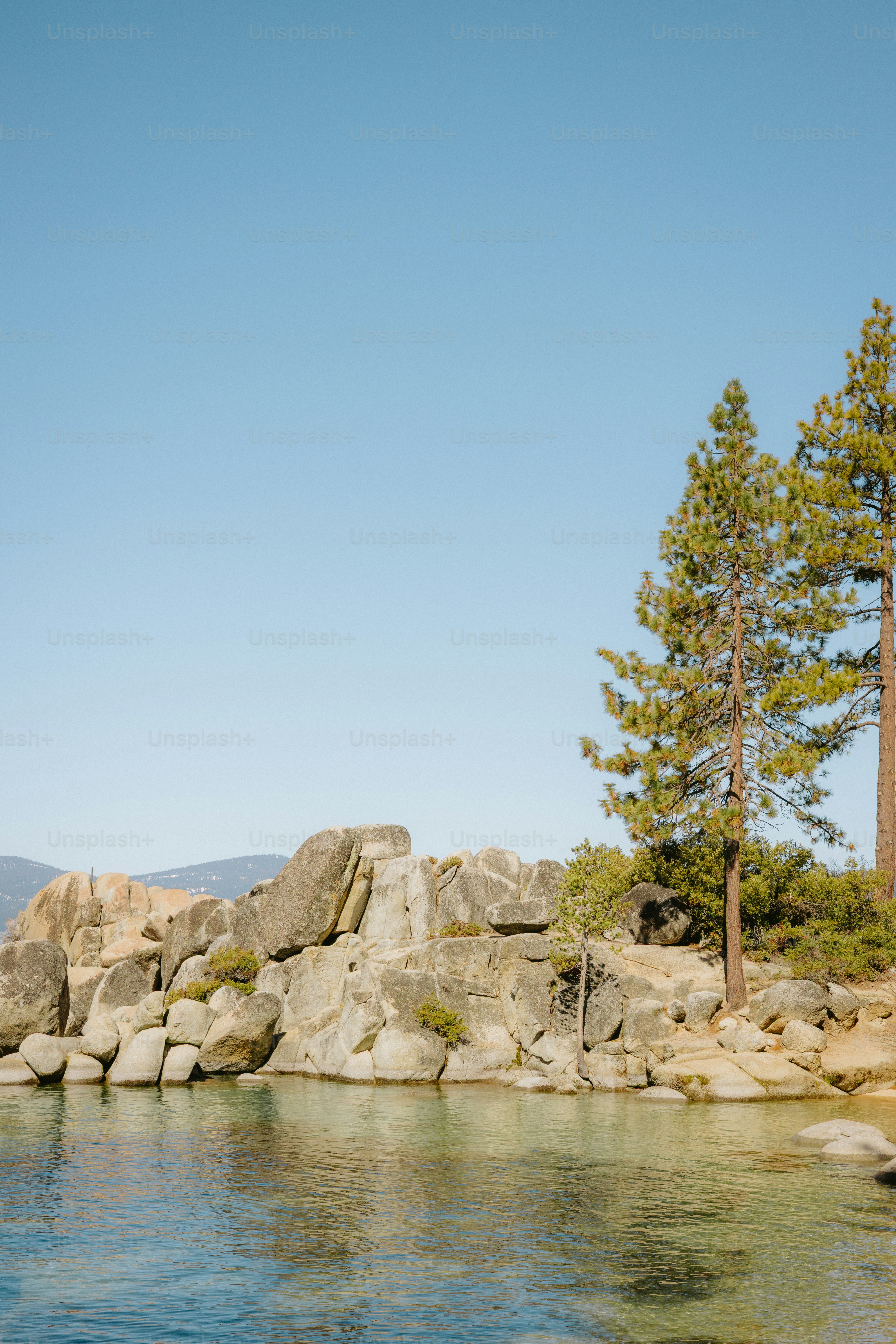 Rocky shoreline meets clear water under a blue sky.