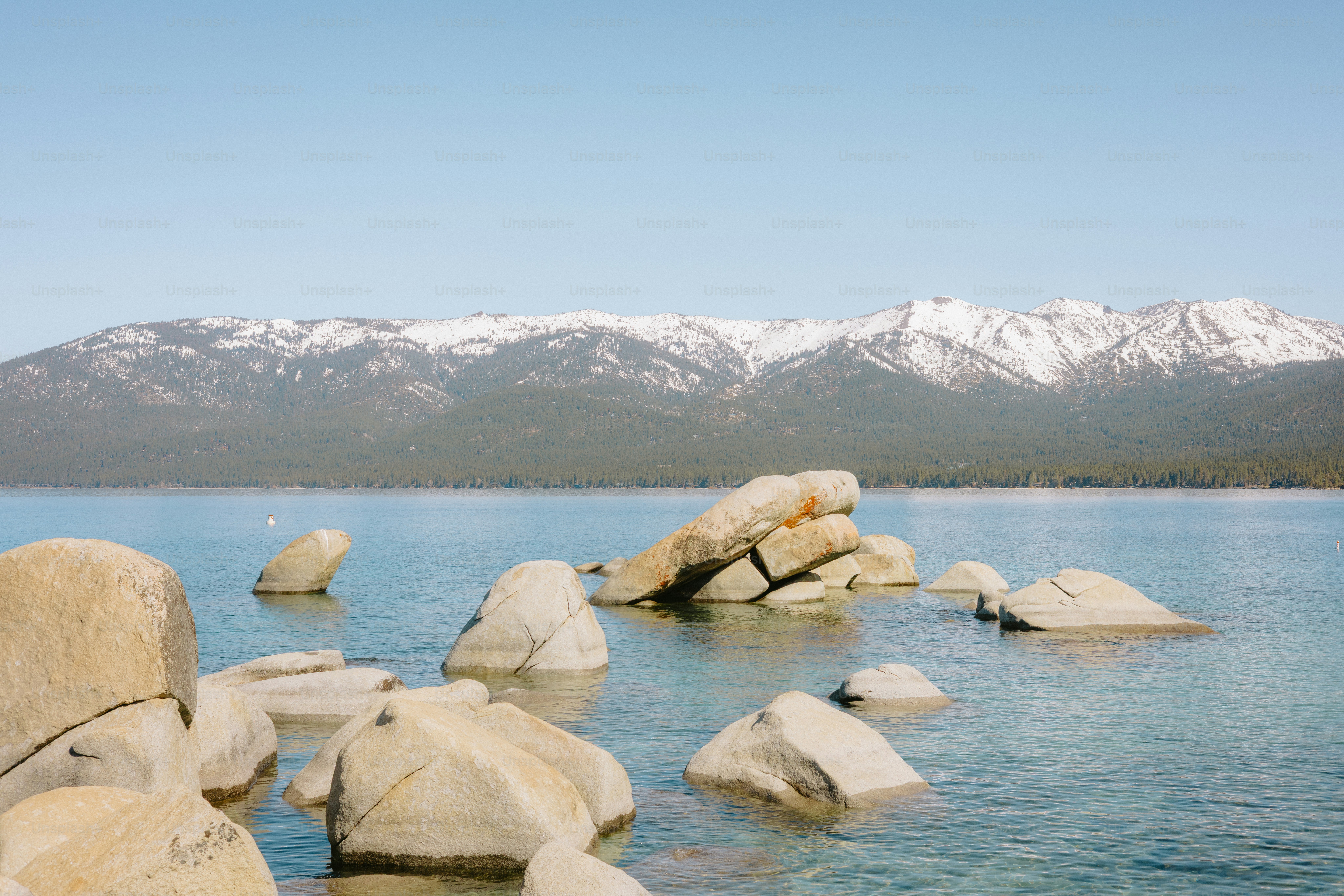 Des rochers dans l’eau, des montagnes au loin.