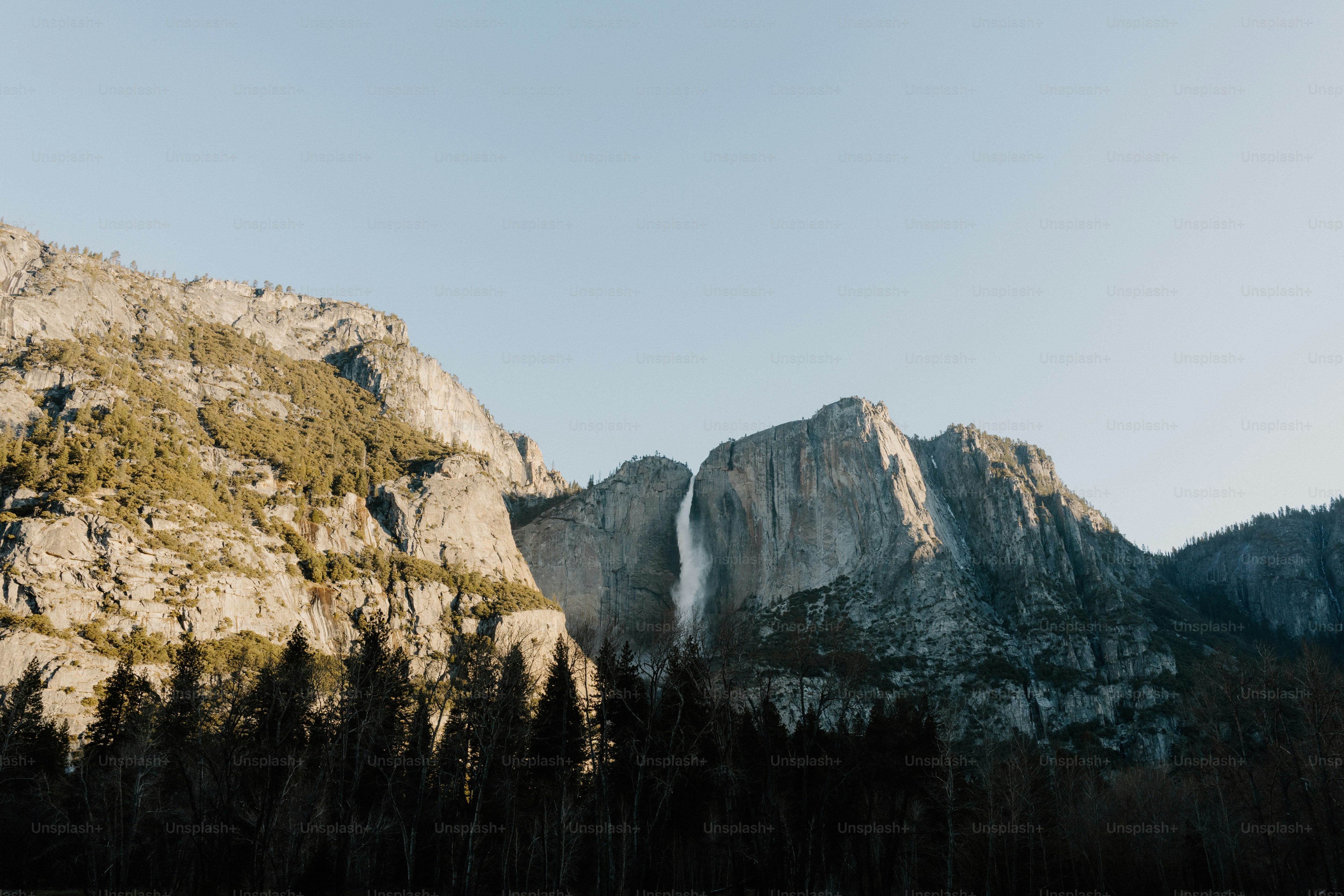 Mountains tower over a waterfall on a sunny day