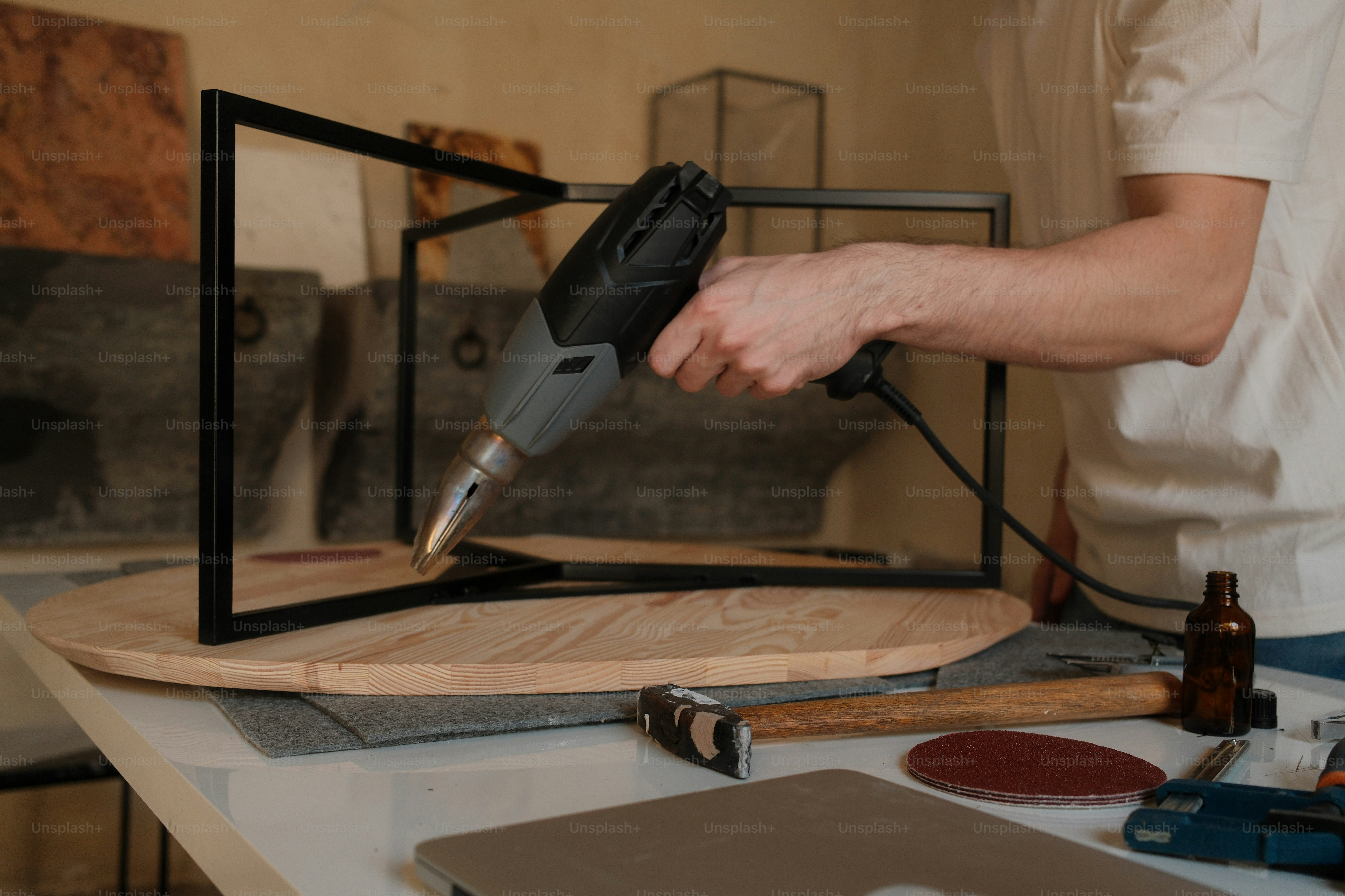 A person uses a heat gun on a metal frame.