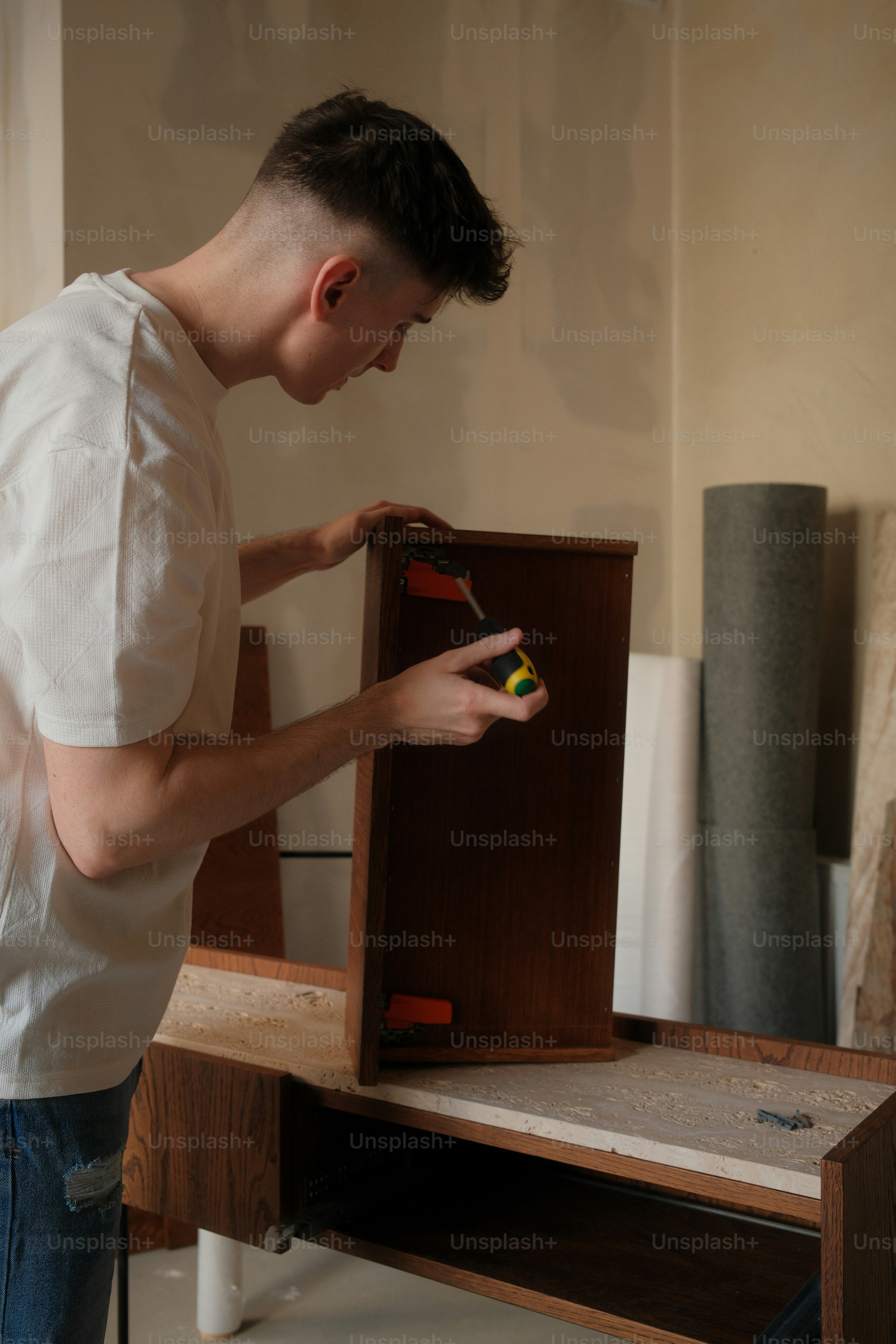 A man is assembling a wooden drawer. photo – Construction Image on Unsplash